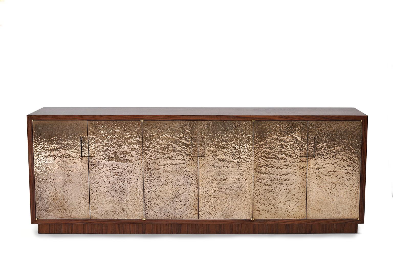 Pacifica cabinet in hammered bronze and walnut. Beautiful cabinet in luxurious Claro Walnut and hand hammered bronze doors.
Hand hammered bronze is a laborious process where the metalworker strikes bronze sheet thousands of times with a polished