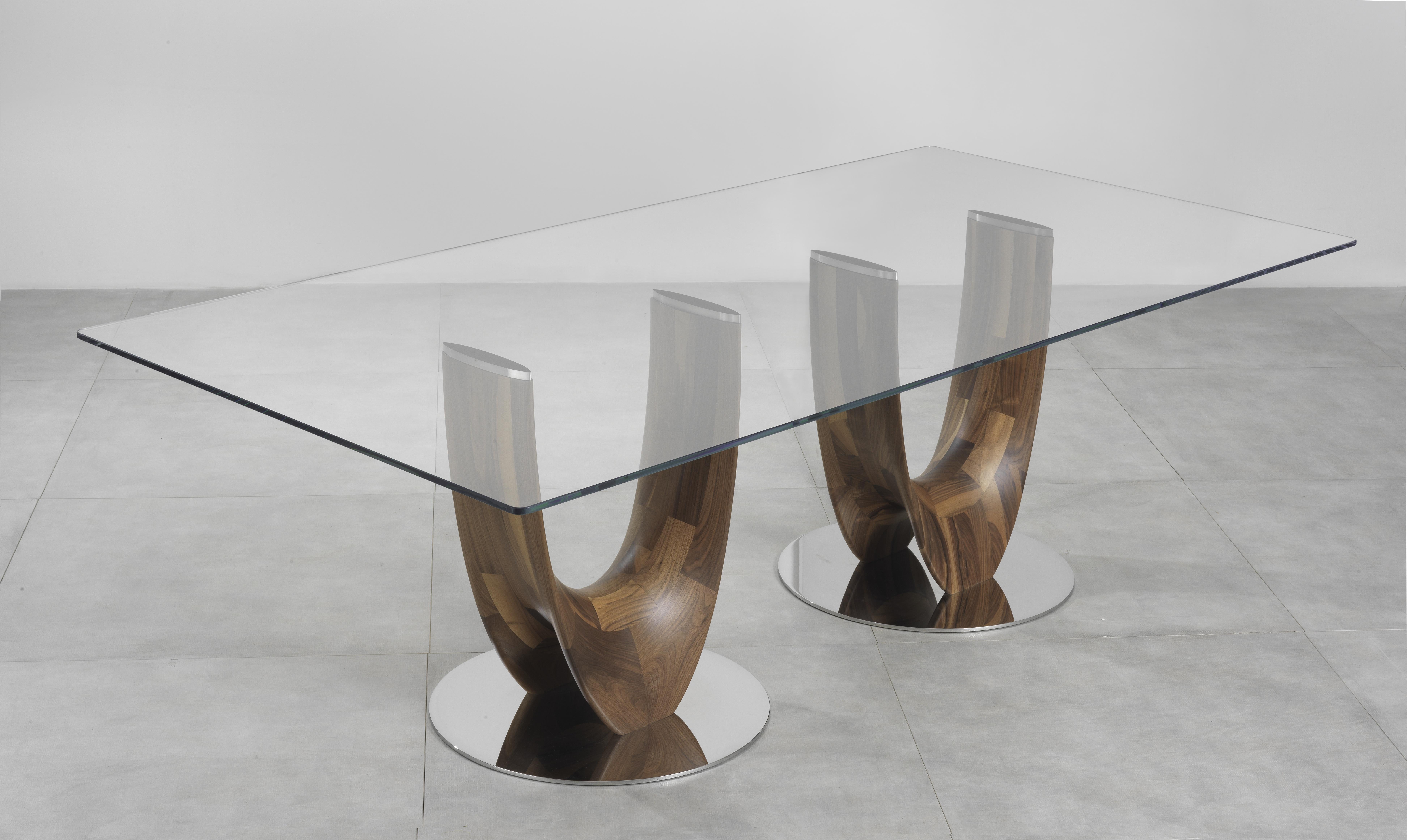 Dining table with base in solid canaletto walnut or ash. Bottom plate in chrome-plated metal. Top in tempered clear or transparent bronze glass (10 or 12 mm th.) with electro welded supports. 

Stefano Bigi studied art in his hometown in France. He