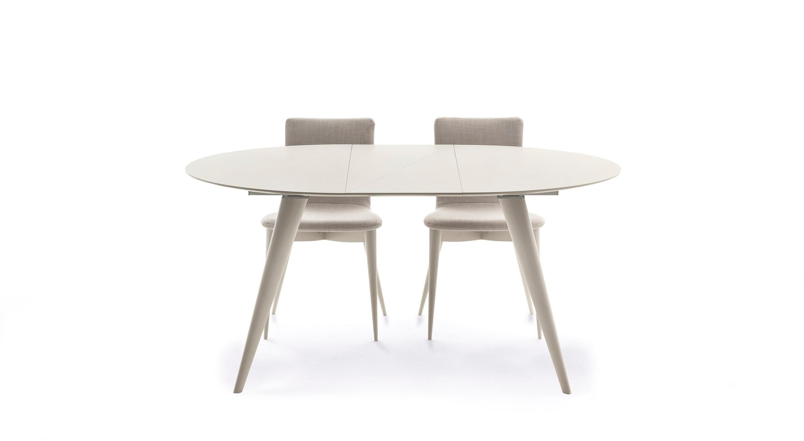 Round extendable dining table with legs in solid ash. Ash veneered top and outside extensions. Aluminium opening mechanism. Available finishing’s: WG wengé, NC walnut, TB tobacco, open pore matte lacquered (L21 white, L29 pearl, L23 cappuccino