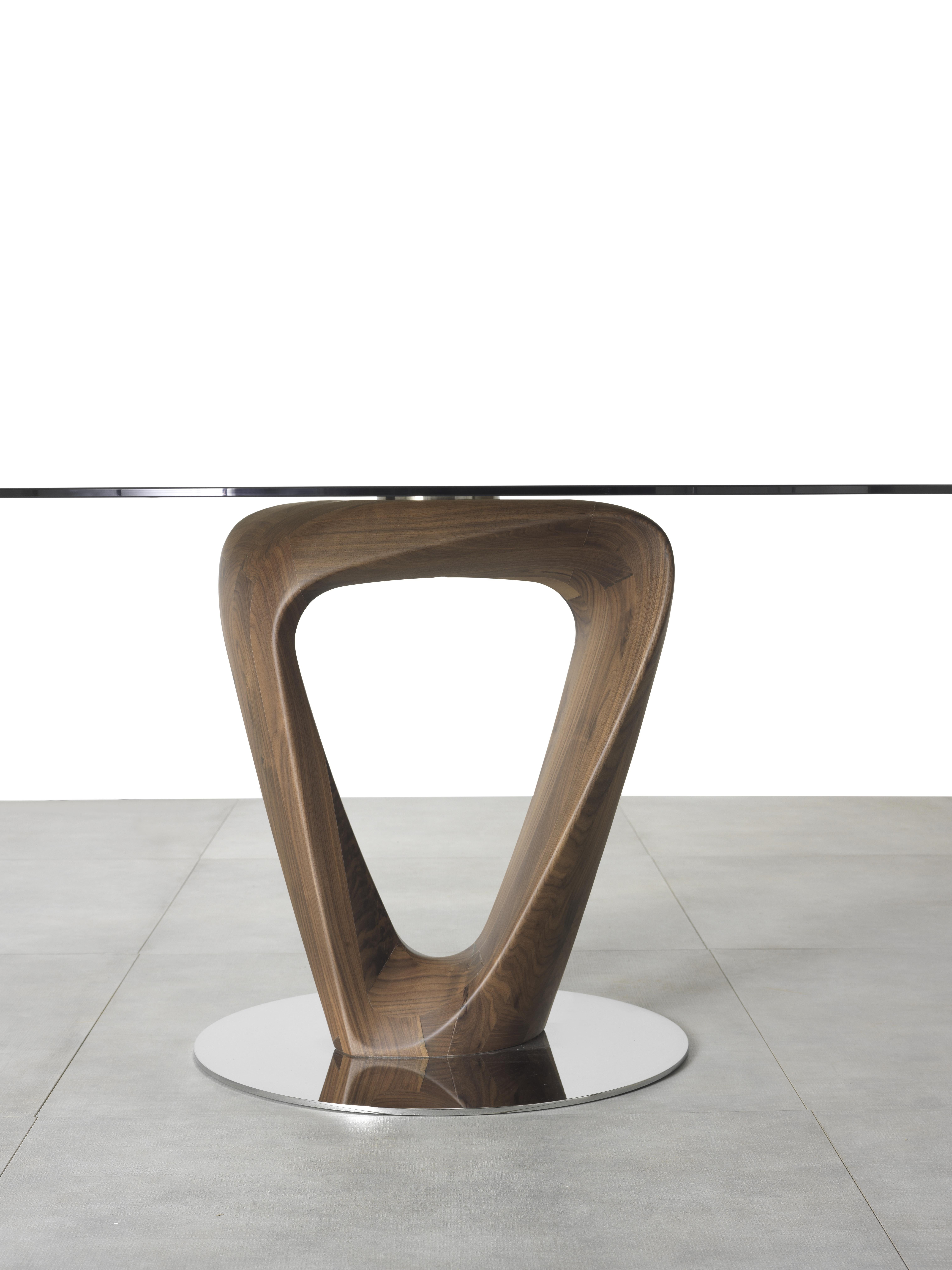 Dining table with base in solid canaletto walnut or ash. Bottom plate in chrome-plated metal. Top in tempered clear or transparent bronze glass (10 or 12 mm th.) with electro welded support. Available finishings: WG wengé, NC walnut, TB tobacco, NK
