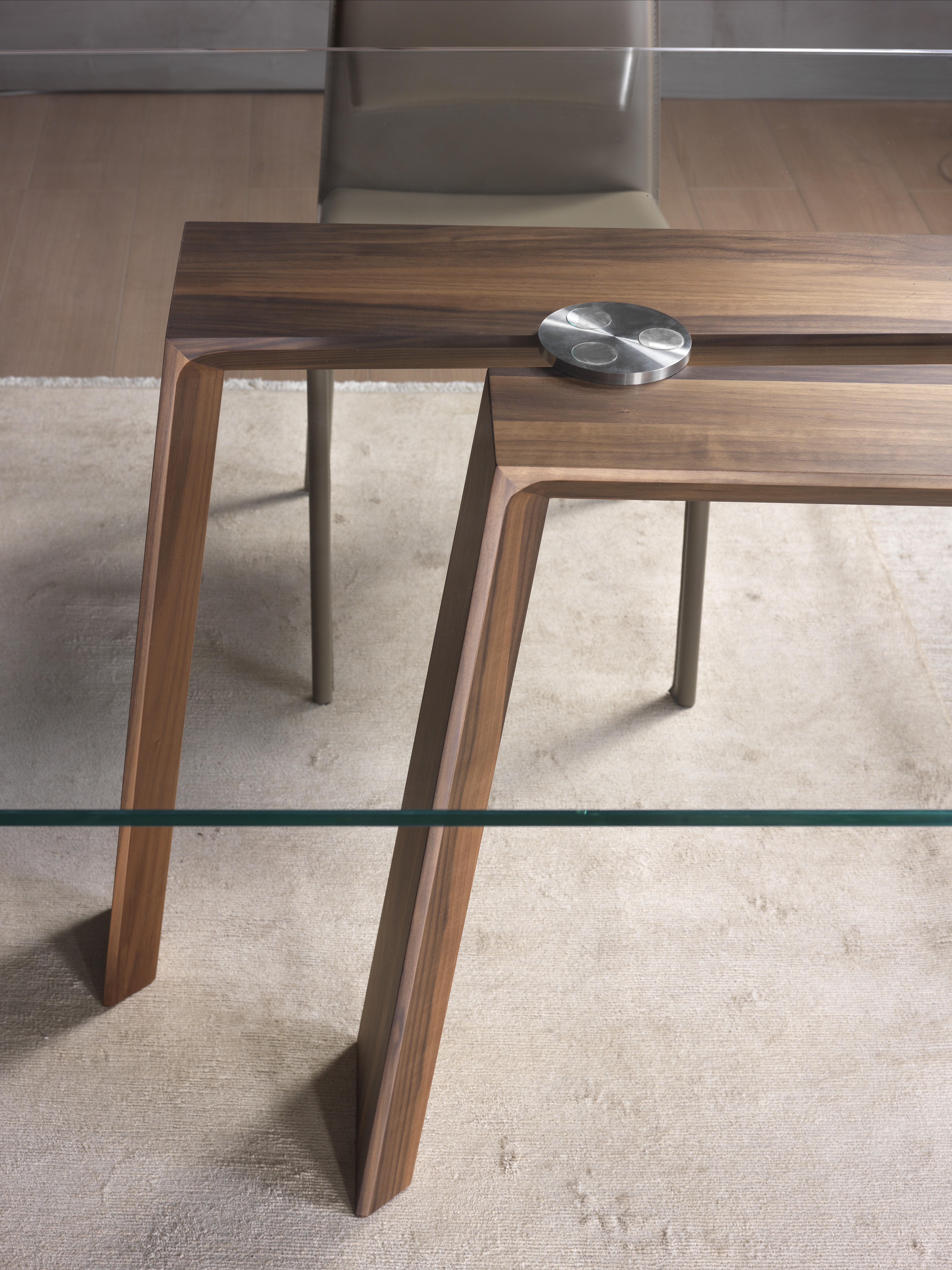 Dining table with supporting bases in solid Canaletto walnut or ash. Top in clear tempered glass (10 or 12 mm thick) with electro welded supports. Available finishings: wengé, walnut, tobacco, Canaletto walnut, open pore matte lacquered (white,
