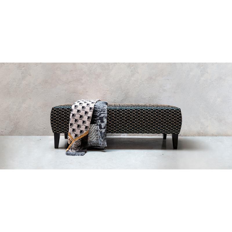 Pièce d'accent chic pour les intérieurs modernes, ce banc exquis dégage un charme intemporel, tapissé de l'élégant tissu Kogo en satin brodé de monogrammes dorés. Reposant sur une structure en contreplaqué laqué noir mat, elle est paddée de mousse