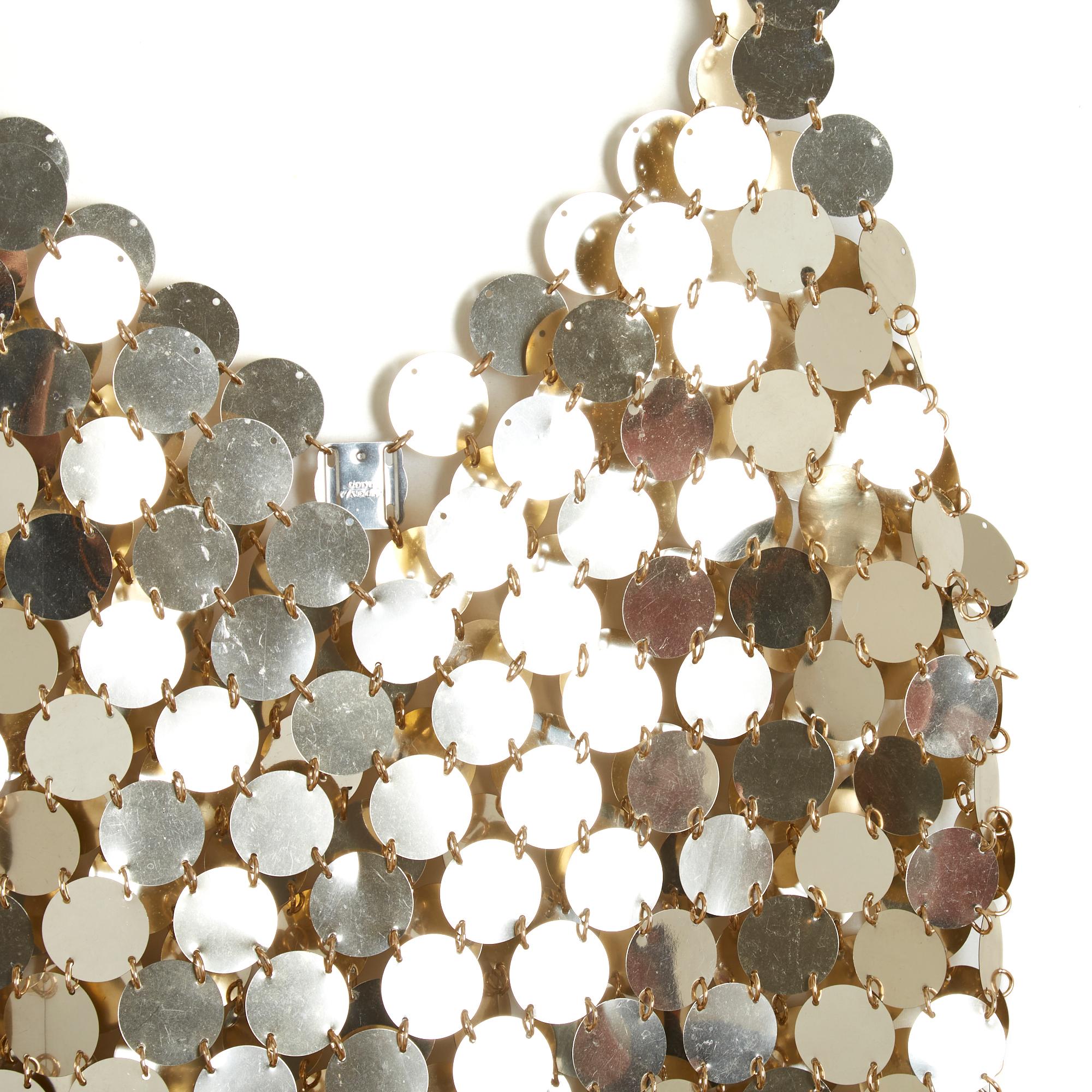 Vestido Paco Rabanne 1994 (para montar tú misma, originalmente) de grandes lentejuelas de plástico doradas y anillas de metal dorado, placa de la firma Paco Rabanne de metal plateado en la espalda. No hay etiqueta de talla, pero las medidas indican