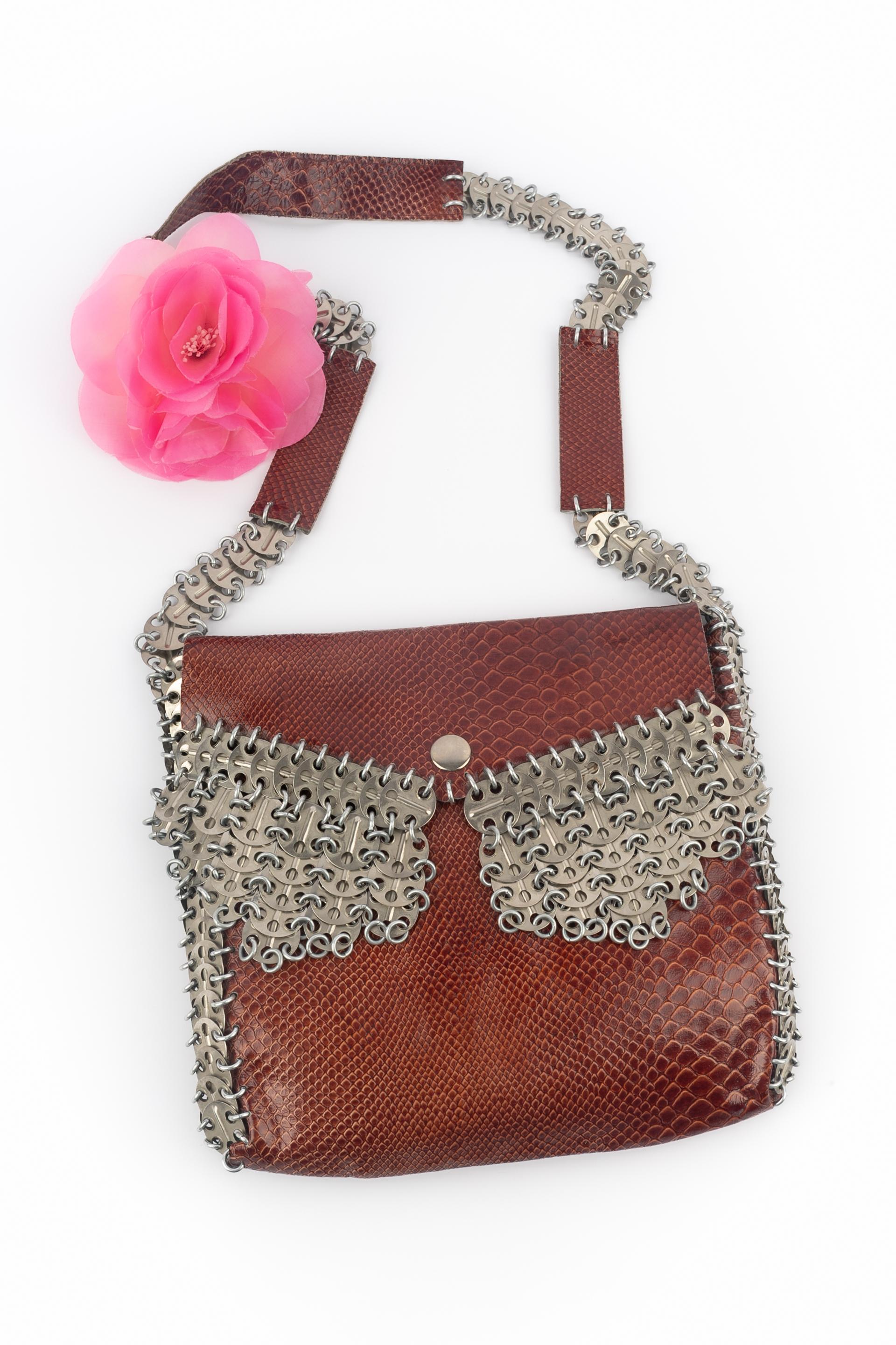 PACO RABANNE - Exotische Crossbody-Tasche aus Leder mit silbernen Metallringen und Pastillen.

Bedingung:
Guter Zustand

Abmessungen:
Länge: 22 cm - Höhe: 24 cm - Tiefe: 4 cm - Stiel: 90 cm

SKU:S98