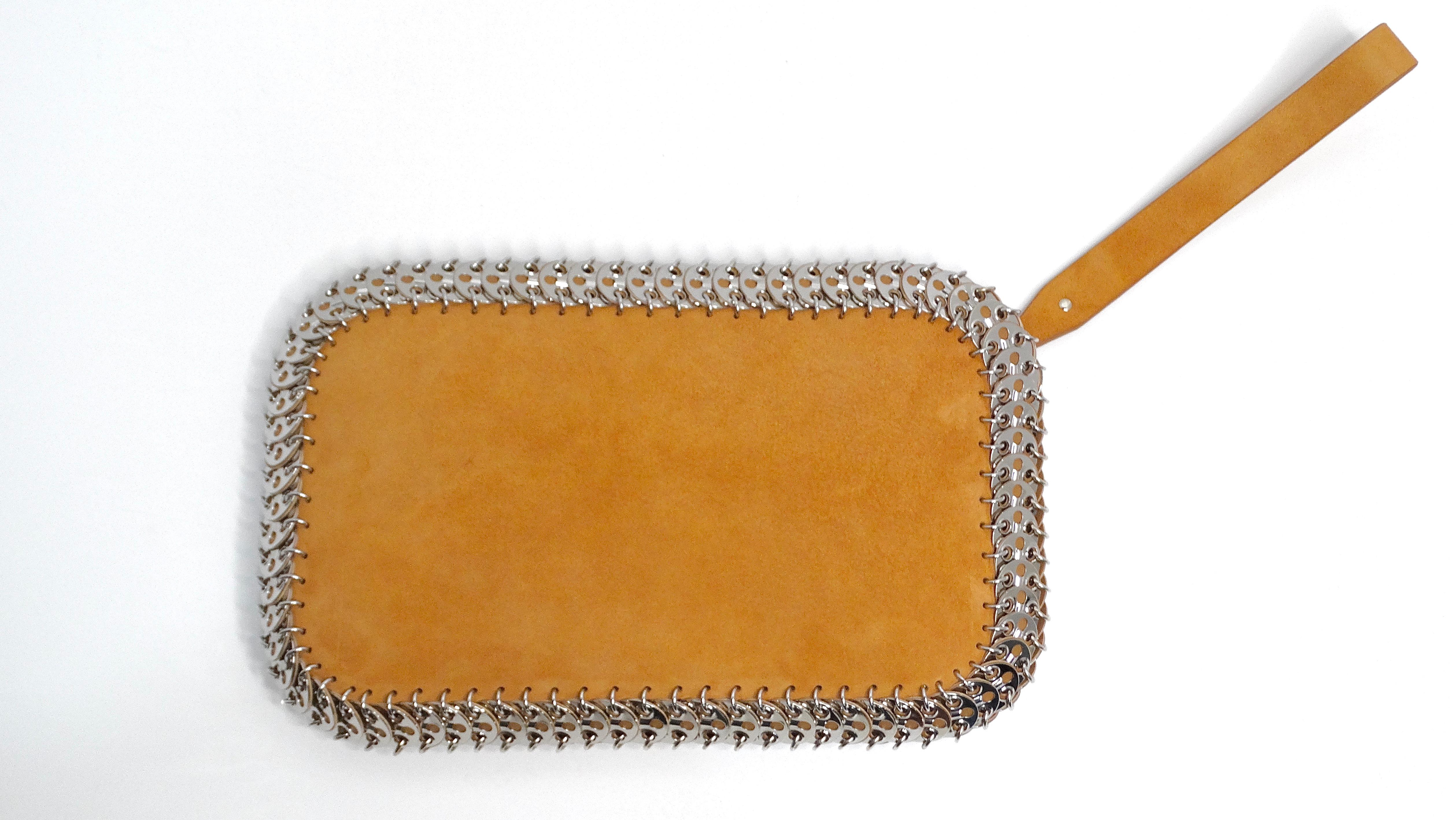 The Paco Rabanne Brown Suede Wrist Pouch is a chic and edgy accessory that seamlessly transitions from day to night. Crafted from warm brown suede, this pouch features a sleek and simple design enhanced by a distinctive silver chain stitch detail