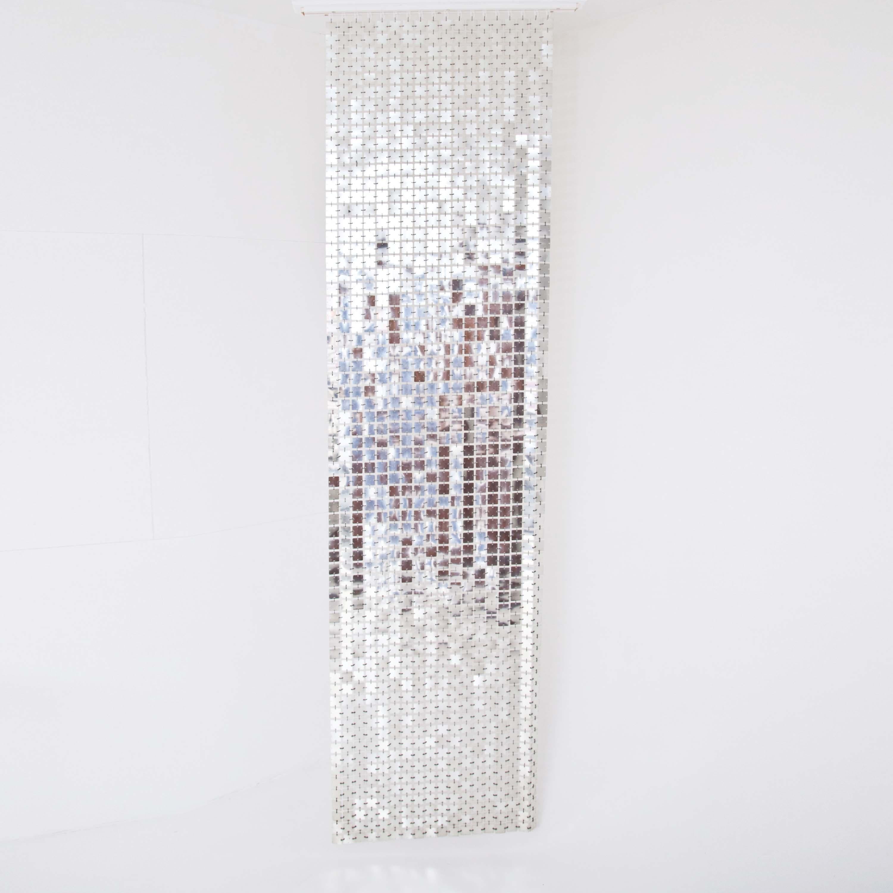 Narrow curtain of thin metal plates in the style of his couture dresses from the 1960s. The squares are all each individually linked by small hooks.