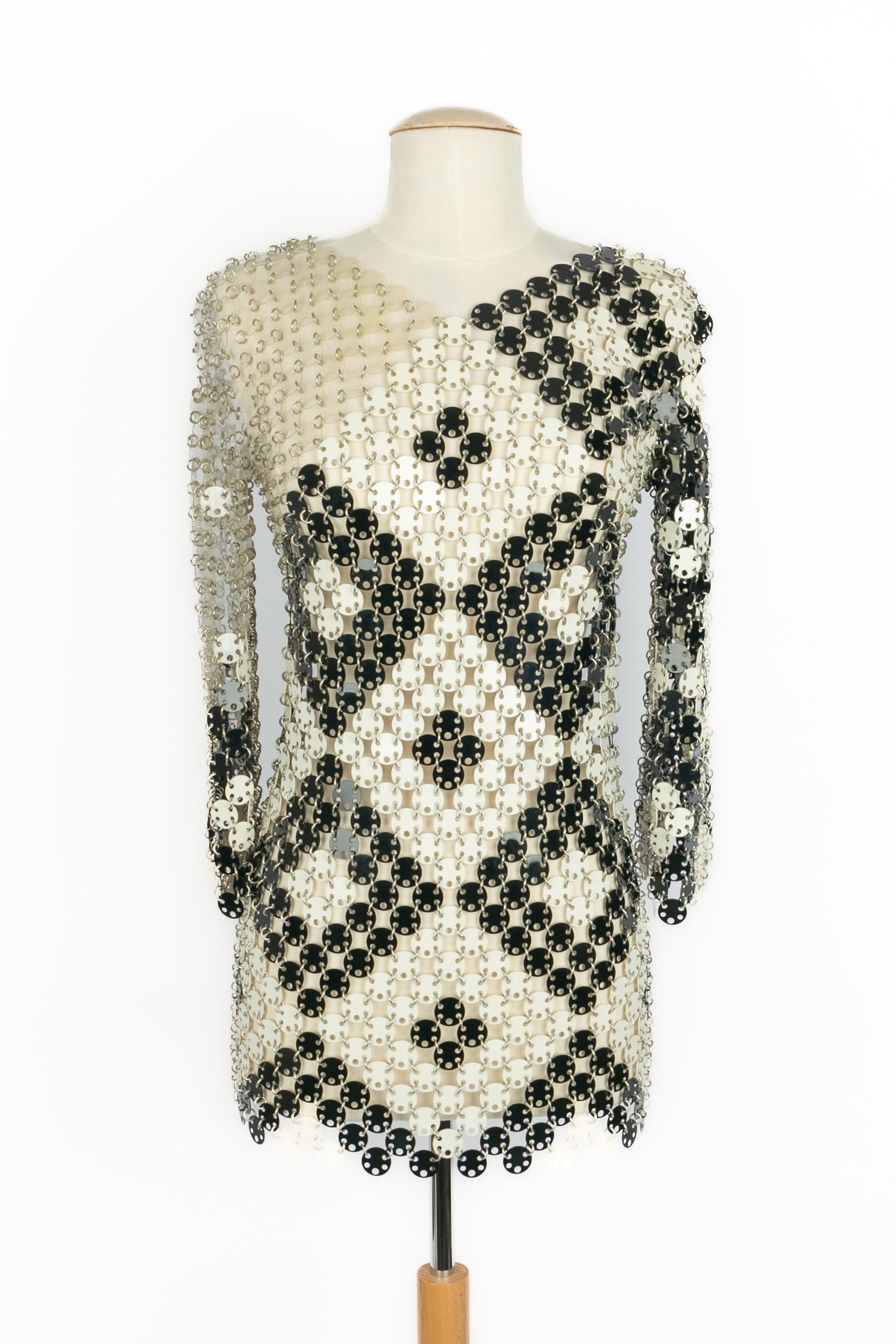 PACO RABANNE - Robe courte composée de pastilles de rhodoïd transparentes, noires et blanches attachées par des anneaux métalliques. Aucune taille n'est indiquée, il convient à un 34FR/36FR. Le nom de la marque n'apparaît pas. Collectional
