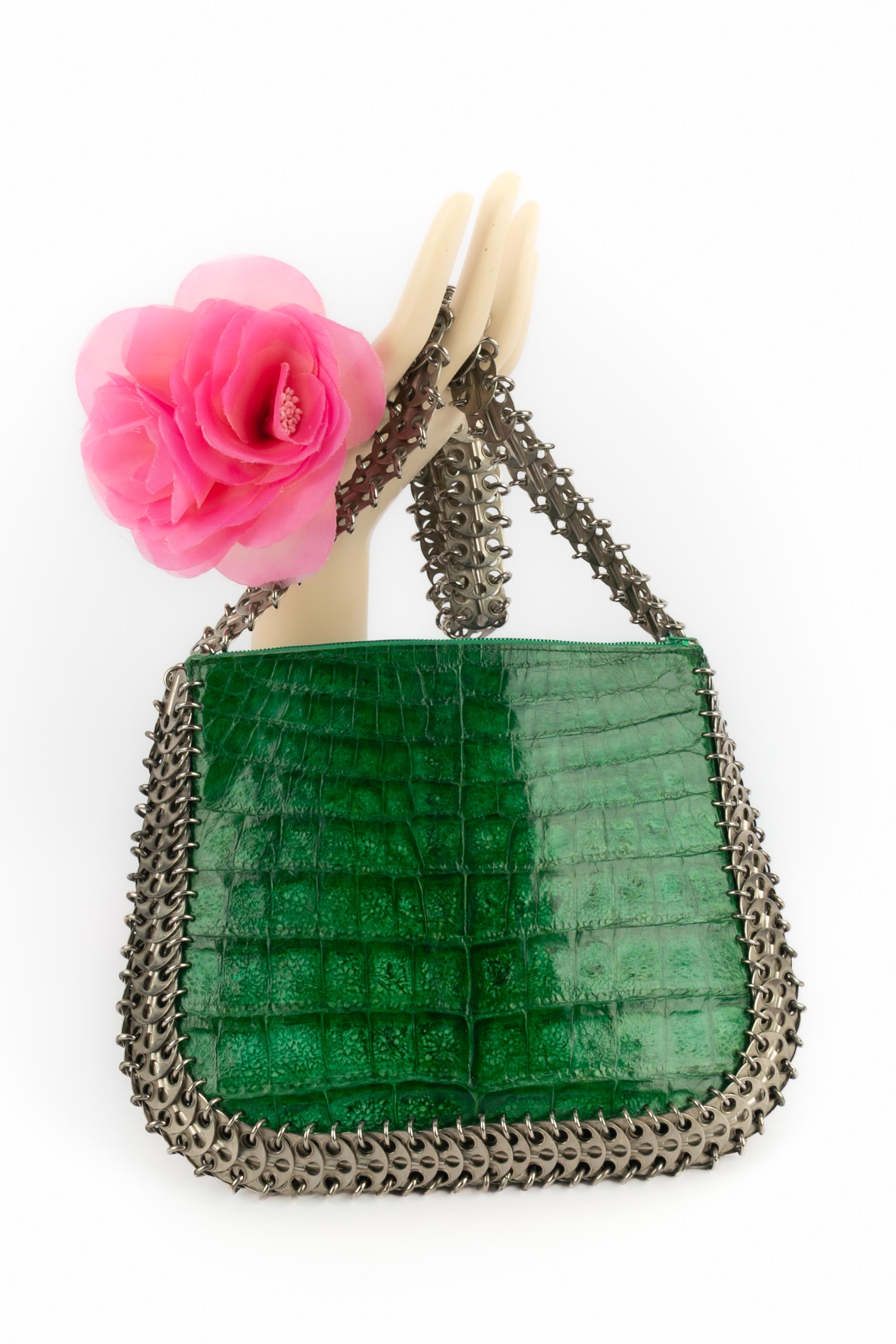 PACO RABANNE - (Fabriqué en France) Sac en alligator couleur émeraude brillant, garni de pastilles percées en métal argenté, avec une anse.

Condit :
Très bon état.

Dimensions :
Hauteur : 20 cm - Largeur : 25 cm - Poignée : 68 cm

SKU:S45