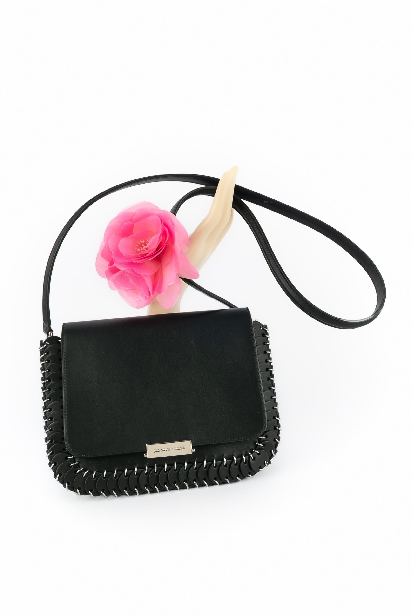 PACO RABANNE - (Made in Italy) Bolso de piel negra con solapa, pastillas de piel, anillas de metal plateado y correa de piel negra extraíble.

Estado:
Buen estado

Dimensiones:
Longitud: 24 cm - Altura: 16 cm - Profundidad: 2 cm - Asa: 106