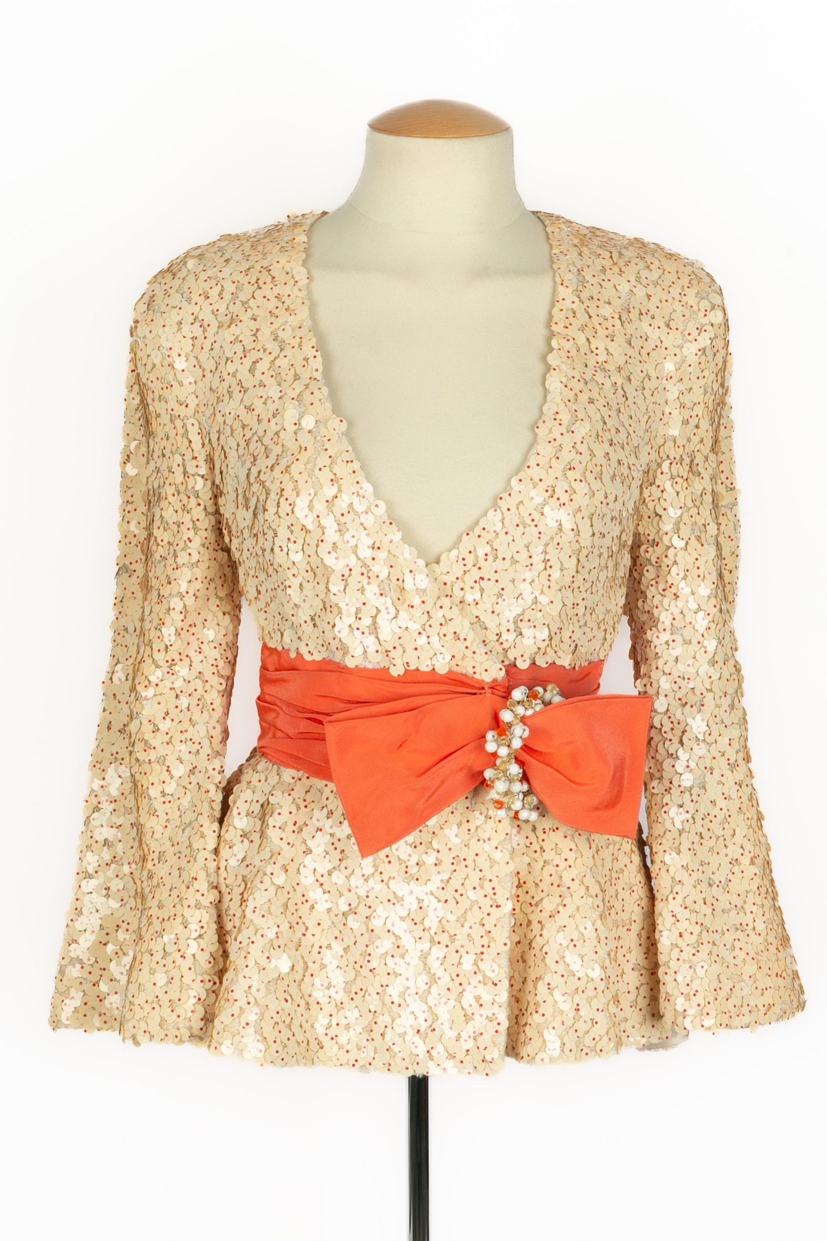 PACO RABANNE - (Fabriqué en France) Veste en laine blanc cassé irisée, brodée de paillettes rouges pointillées couleur crème. Ceinture ottomane couleur corail rehaussée d'une boucle perlée. Aucune taille n'est indiquée, il convient à un 36FR.