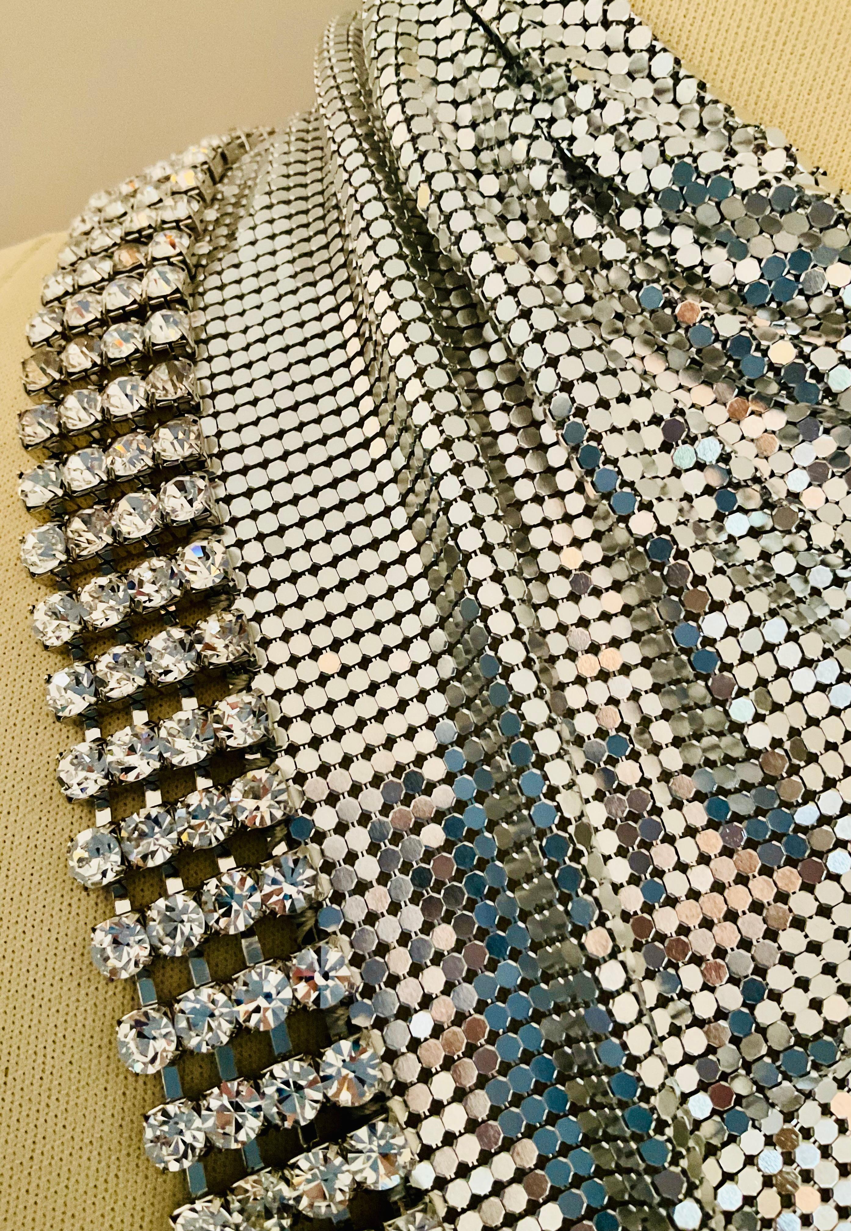 Esta obra maestra de edición limitada, un raro pañuelo triangular de malla metálica de H&M para Paco Rabanne, fusiona el arte futurista con la alta costura ponible, confeccionada con una brillante malla metálica adornada con pedrería, una