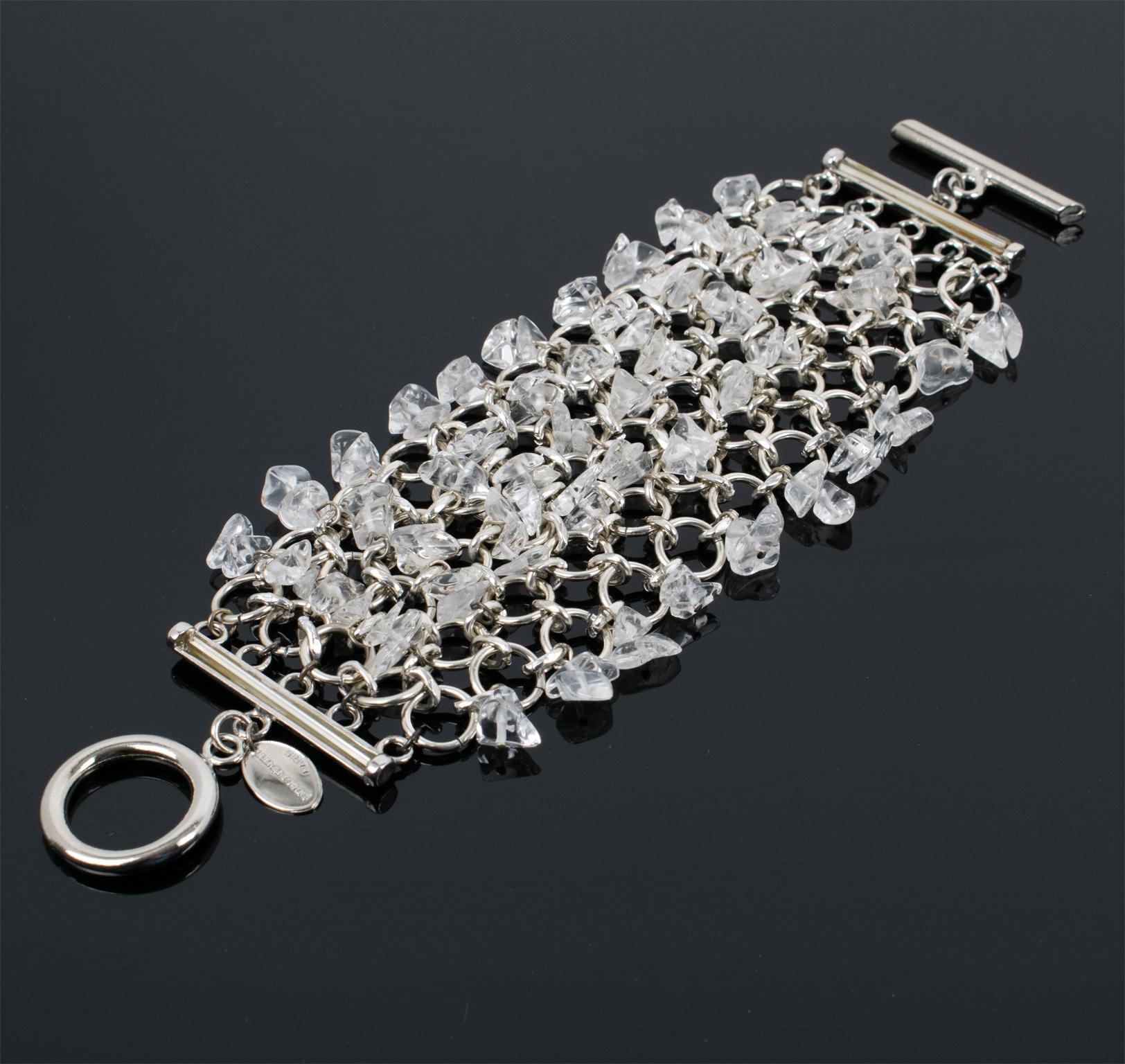 This gorgeous Paco Rabanne Paris futuristic link bracelet features a massive silver-tone chainmail grid ornate with dangle transparent quartz chips. The bracelet closes with a large toggle closing clasp, and the Paco Rabanne brand logo tag is