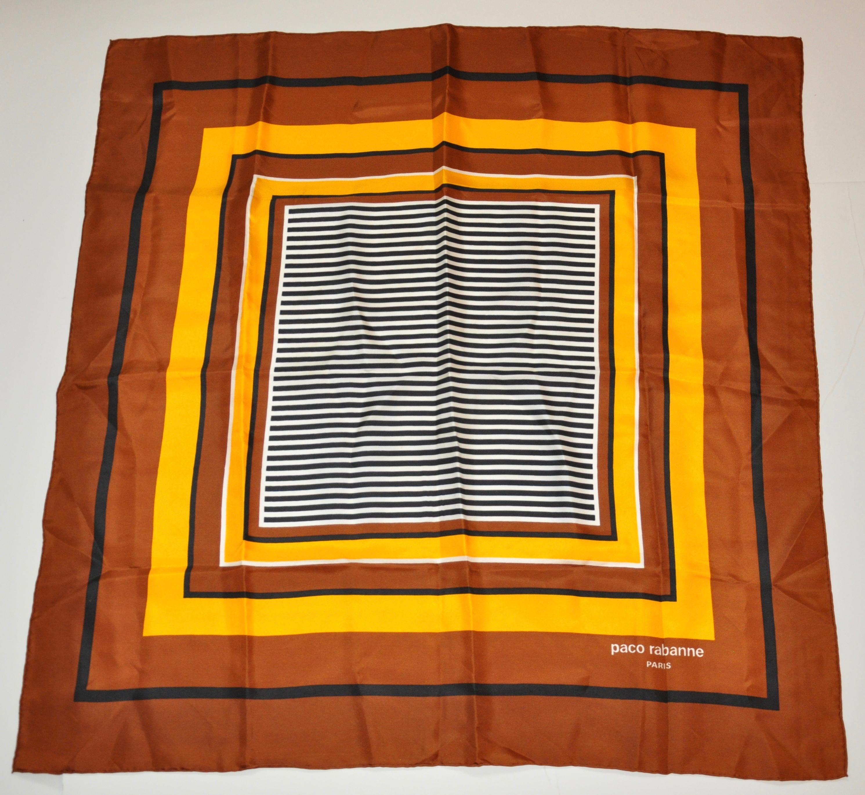     L'écharpe en soie de Paco Rabanne présente de riches nuances de brun et de jaune accentuées de noir autour d'un centre rayé. Elle mesure 30 pouces par 31 pouces. Les bords sont roulés à la main et fabriqués en France.