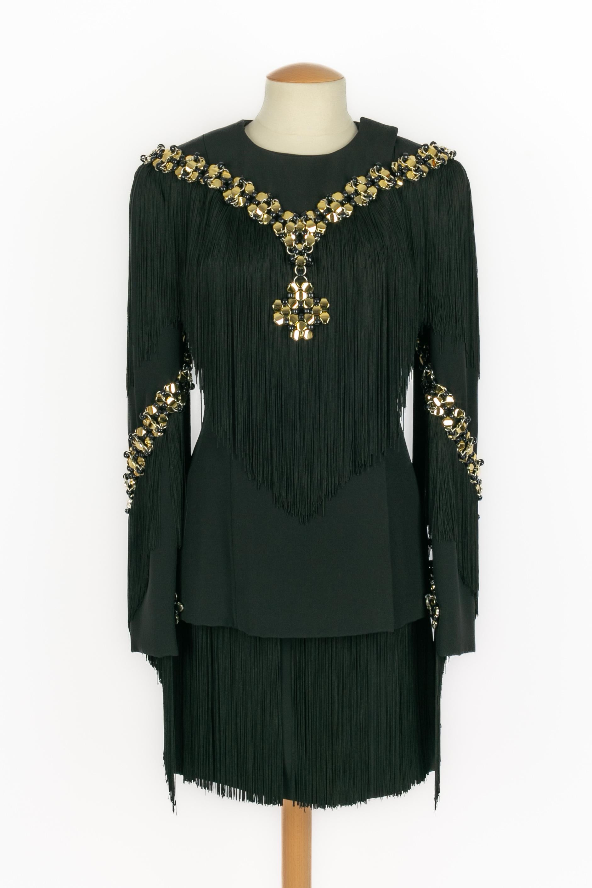 PACO RABANNE -  Set in crepe di seta nero con frange, composto da una giacca e una gonna. Applicazioni a catena realizzate con elementi in plastica nera e anelli in metallo dorato. Non è indicata la taglia, ma veste una 34FR/36FR. Collezione Haute