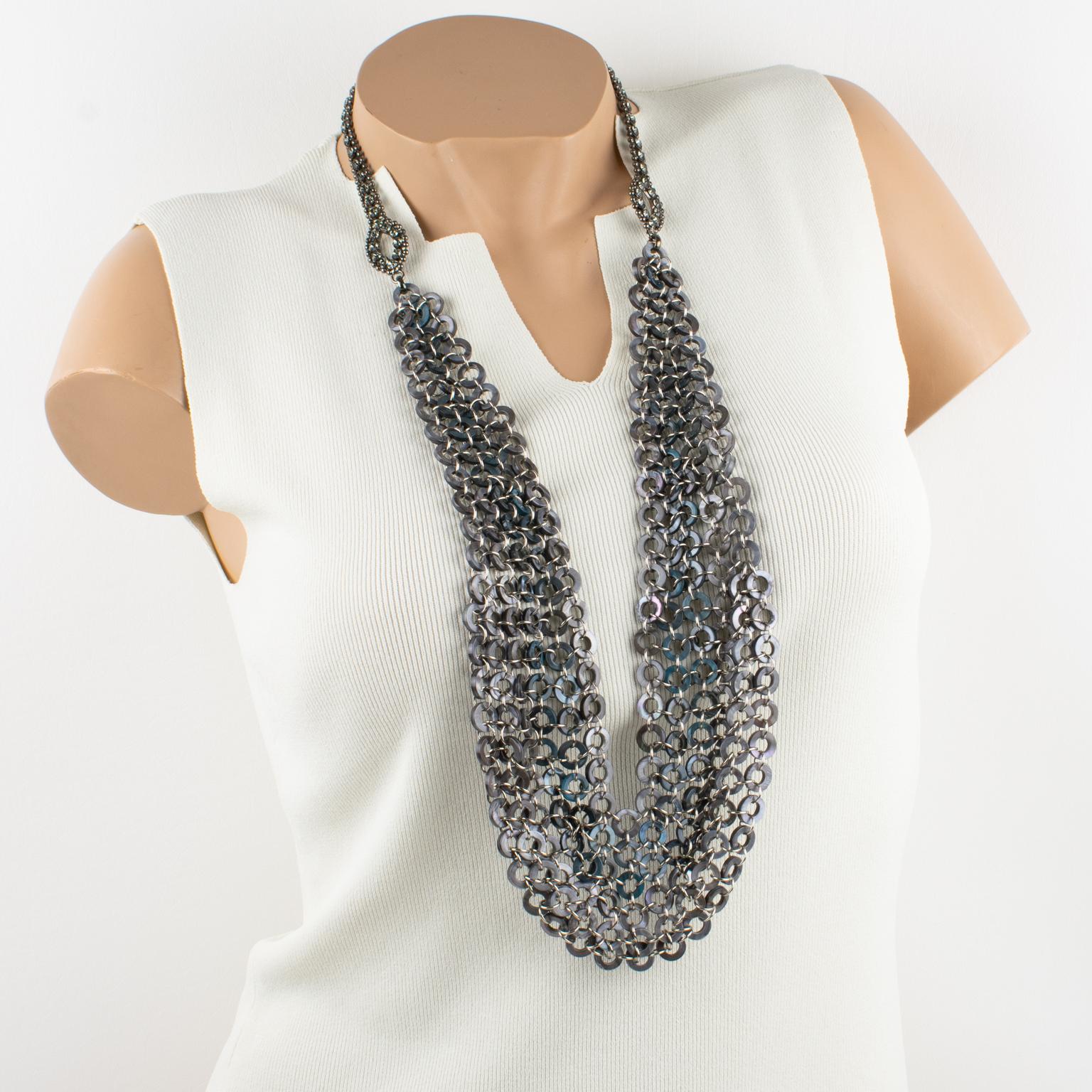 This spectacular French necklace has a gorgeous bib drapery shape built with inter-connecting geometric chromed metal and seashell links. The seashell donut-shaped links have iridescent colors ranging from gray to turquoise-blue. 
Its Extra-long