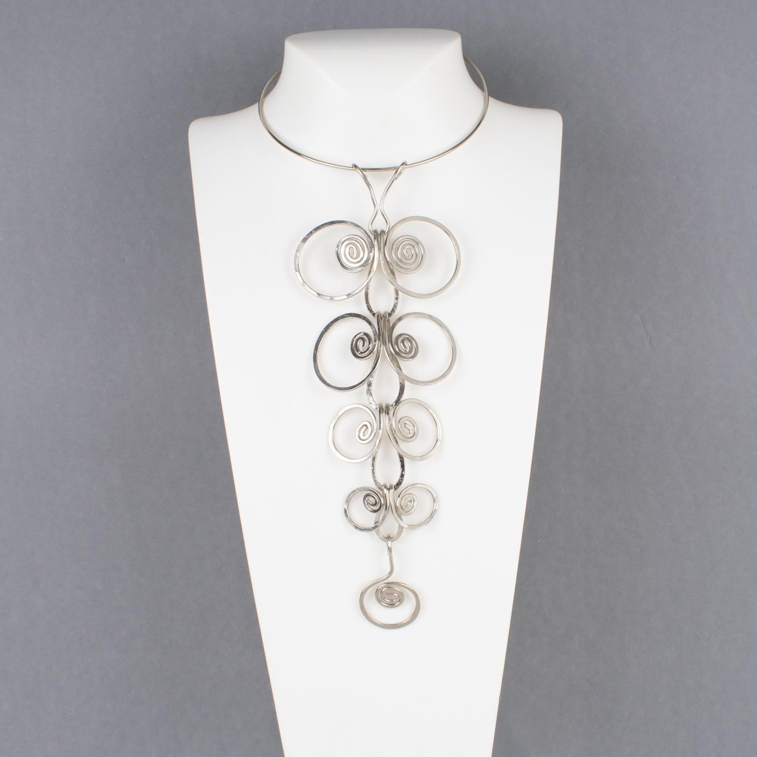 Cet étonnant long collier moderniste en métal NO AGE avec un pendentif géométrique des années 1970 rappelle le travail de Paco Rabanne. La pièce se compose d'une bande de métal chromé rigide autour du cou, ornée d'un impressionnant pendentif