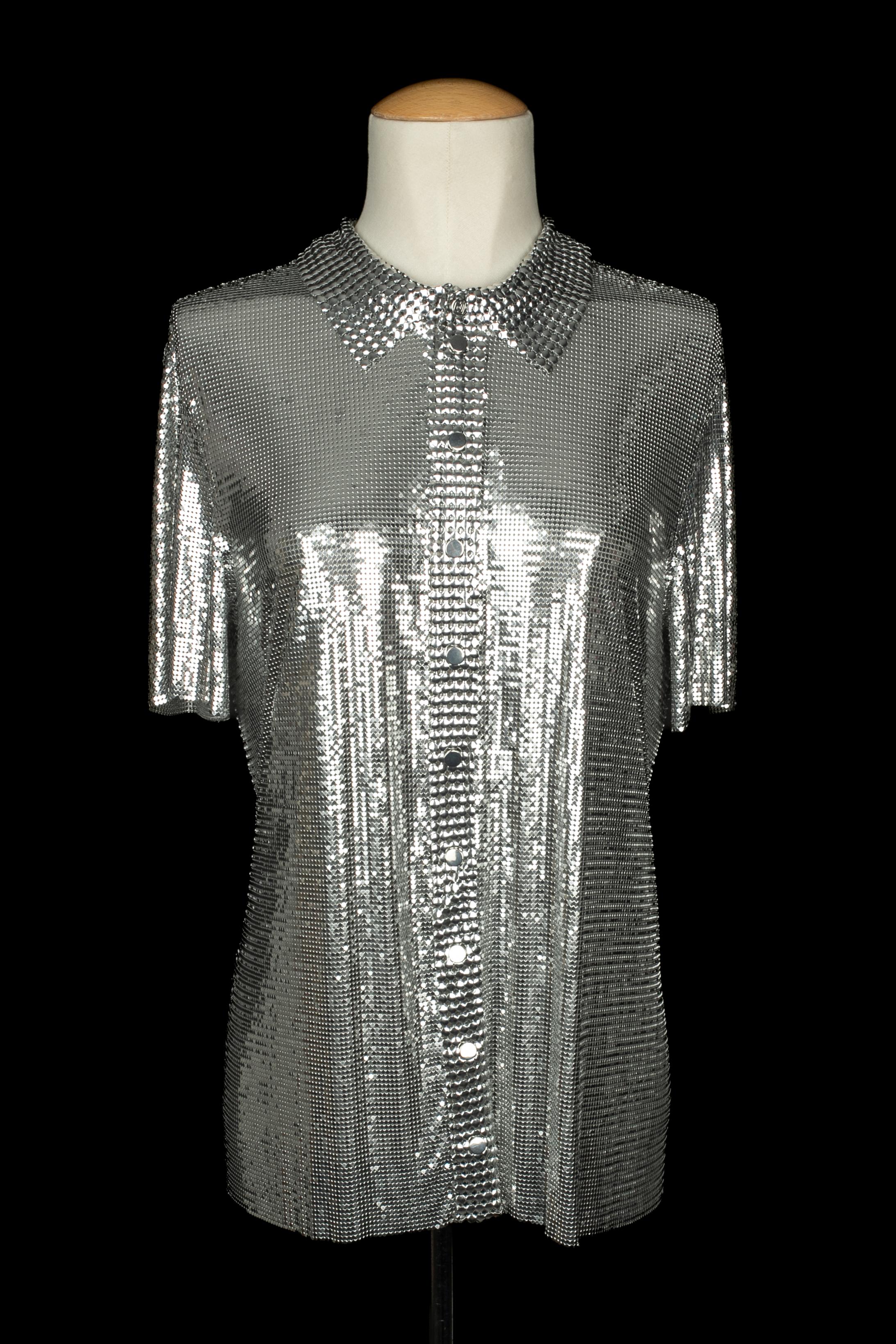 PACO RABANNE - Top in maglia argentata con colletto a camicia e chiusura con bottoni a pressione. La taglia 44IT indicata, corrisponde a una 40FR. Collezione Autunno-Inverno 2013 sotto la direzione artistica di Lydia Maurer.

Condizioni:
Ottime