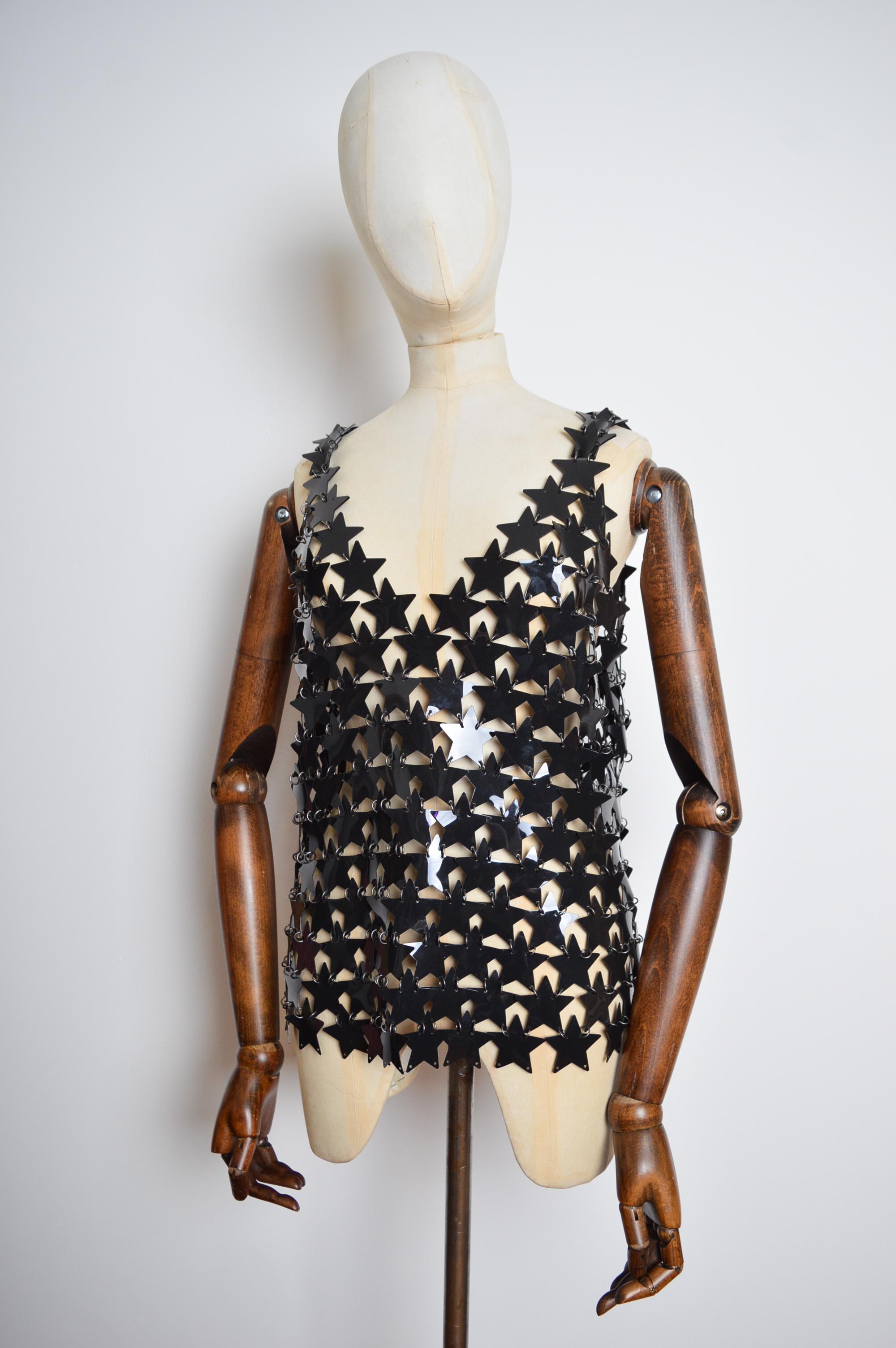 An instantly recognisable, Iconic Paco Rabanne Chain Mail Vest.   

Crafted in Madagascar from Black Star shaped Plastic discs with Silver coloured brass attachments.

The Vest can be worn on a variety of sizes due to the Loose nature of the