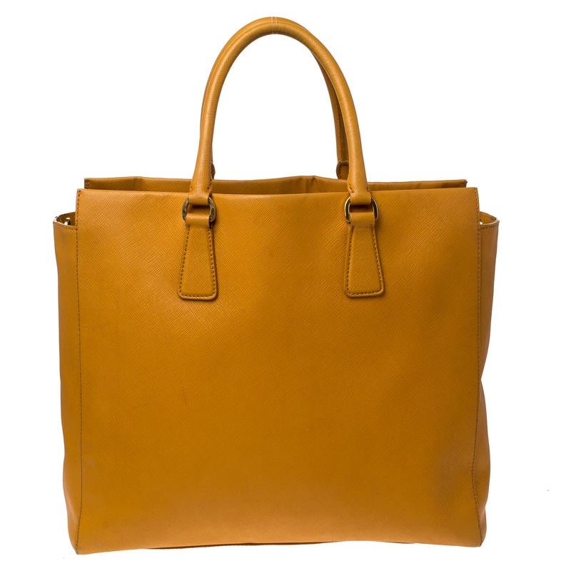 Masterfully crafted with orange Saffiano leather, this bag will make a memorable addition to your collection. Finely lined with monogram-printed fabric, this is a one-stop fashion adornment for all your needs! This Prada bag is splendid for everyday