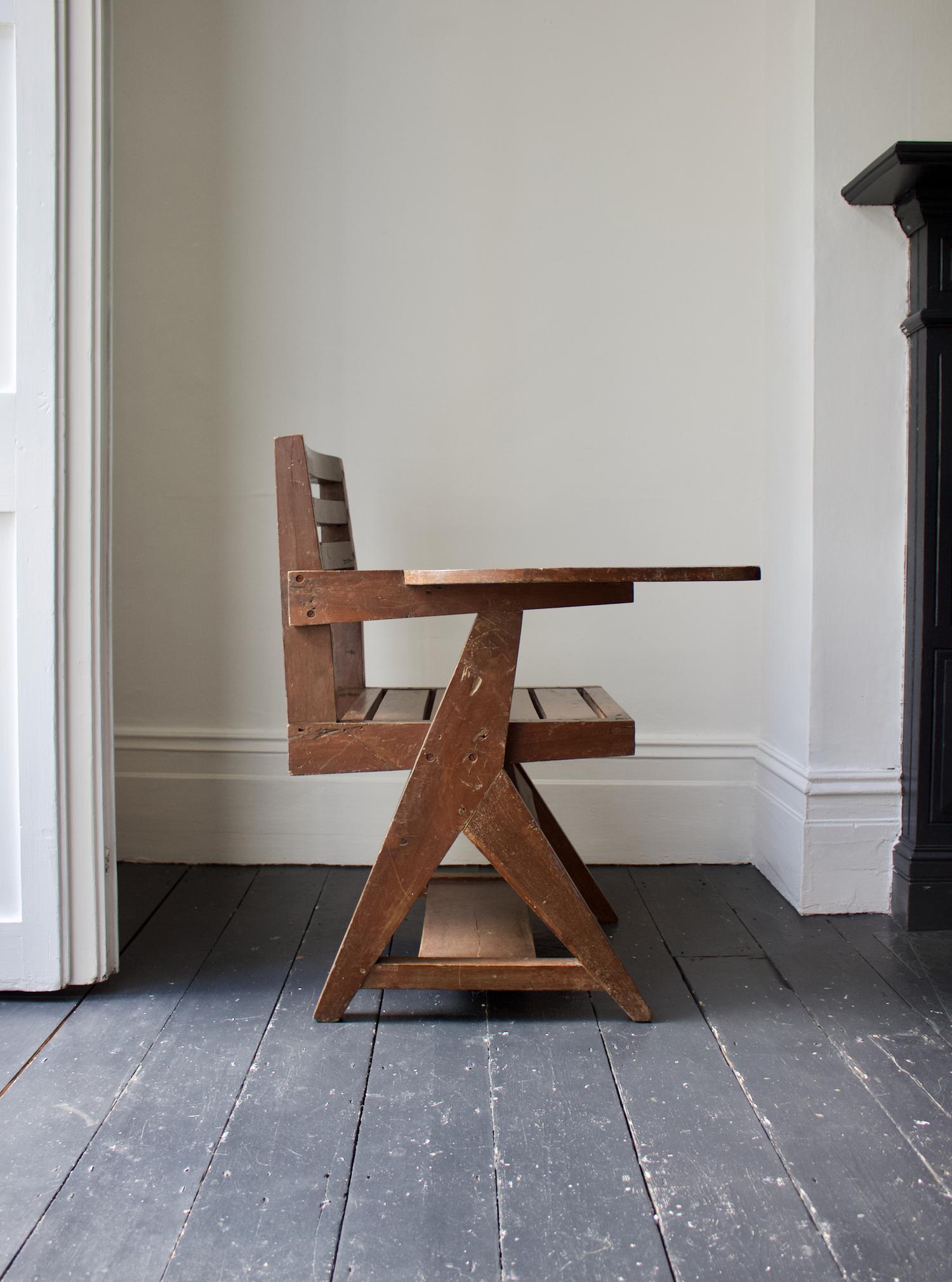 Paddle arm student chair or writing chair attributed to Pierre Jeanneret (1896-1967). 

This all-wood model has an inverted Y leg supporting the fixed writing area and a shelf below the seat. 

A heavy sculptural piece with an aged patina