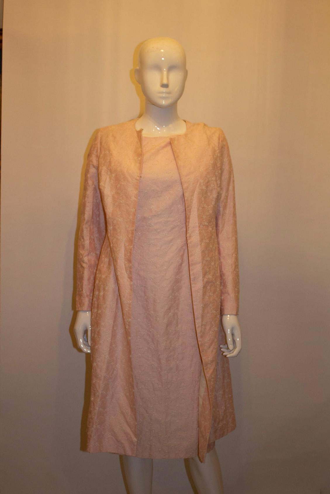 A pretty dress and coat ensemble by Paddy Campbell. In a pink and white colour combination,  the shit dress has a round neckline and back central zip. The coat is collarless . The fabric is a cotton , silk mix and both items are lined.