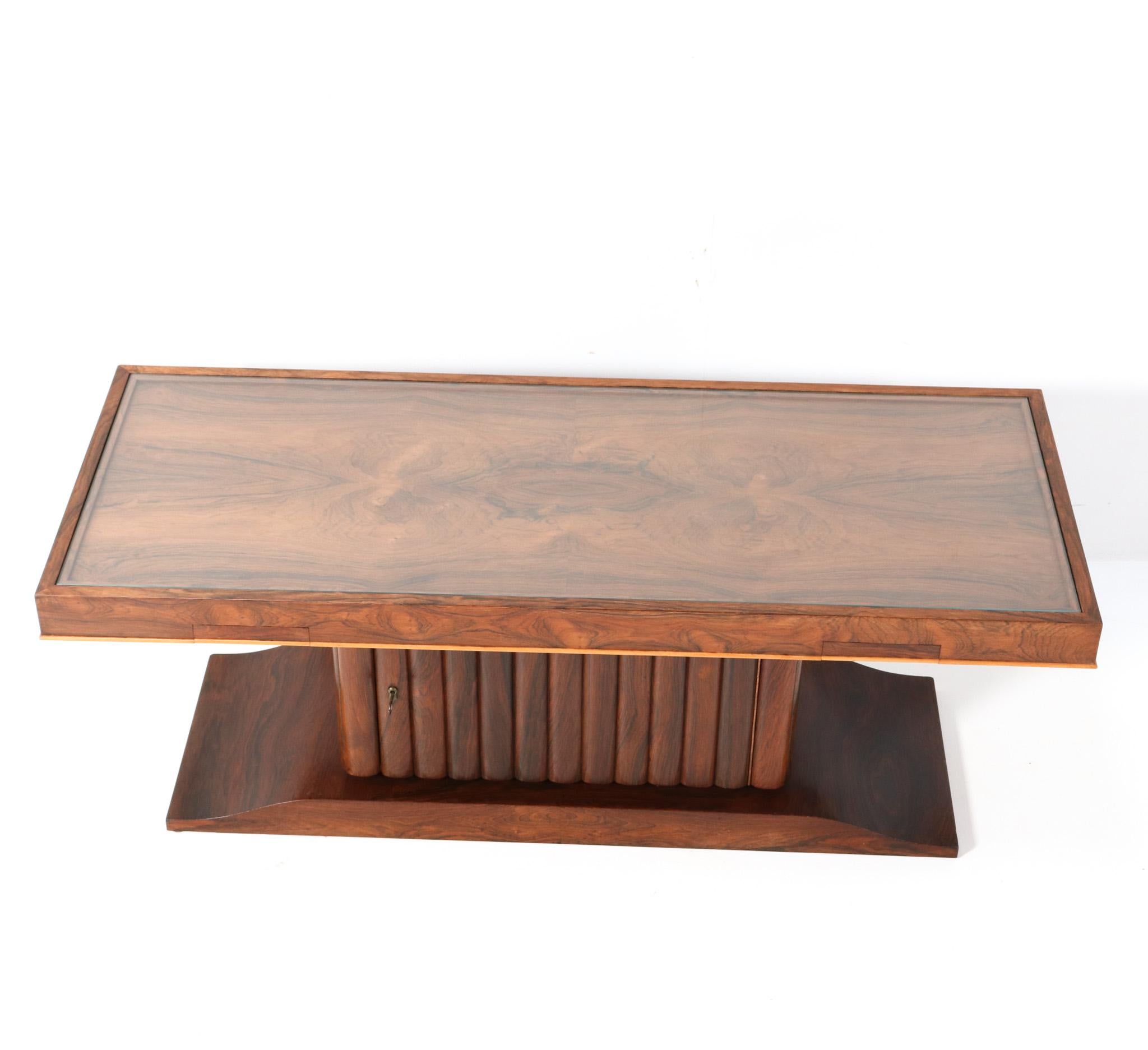 Magnificent and ultra rare Art Deco coffee table or cocktail table.
Design by Gebroeders Reens Amsterdam.
Striking Dutch design from the 1930s.
Solid padouk and padouk veneer base with original padouk veneered top.
Integrated dry-bar with glass