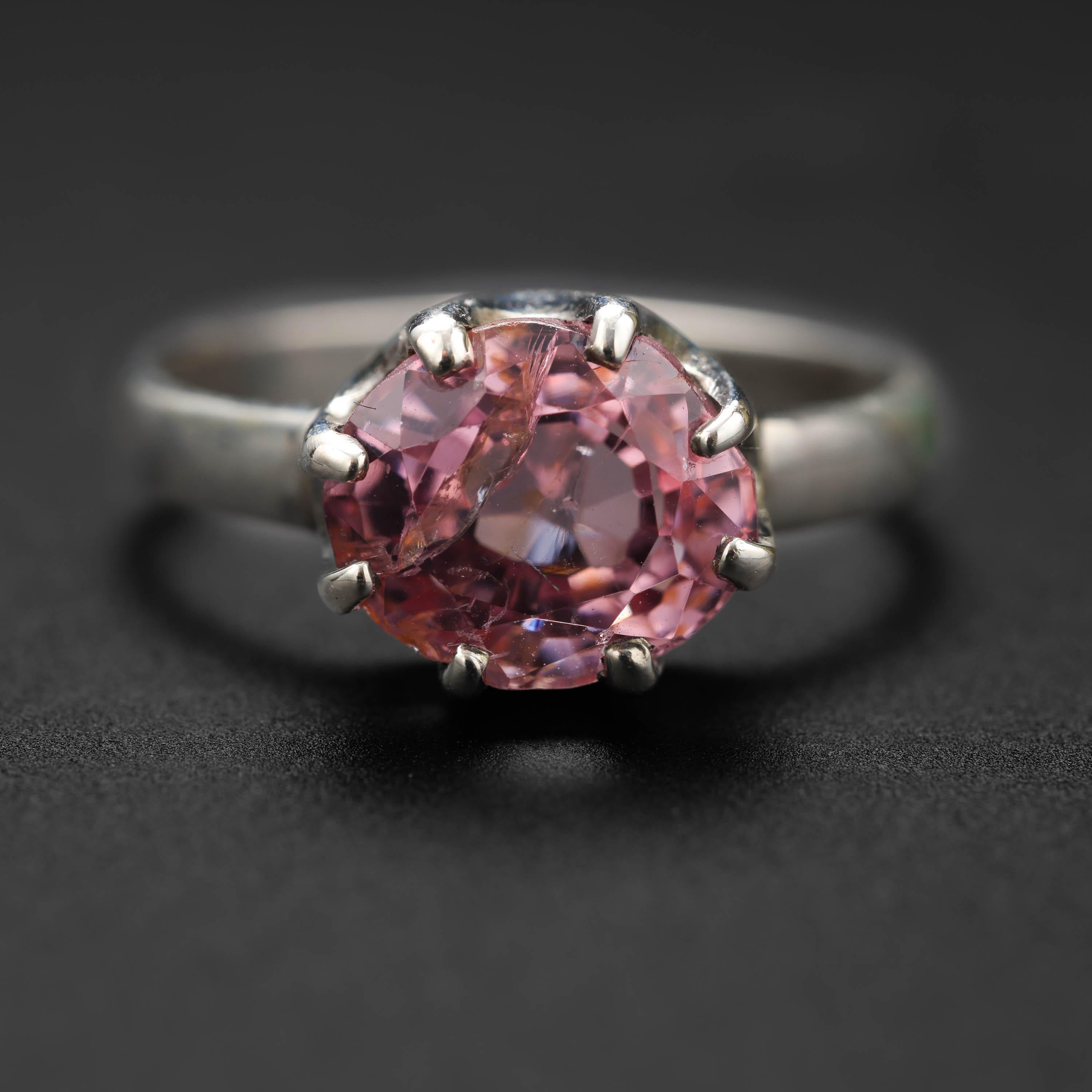 An approximately 2.81 carat oval-cut spinel the color of the finest Padparadscha sapphire is held aloft within the prongs of a formal coronet setting in this rare and magnificent Danish Modern silver ring dating to the 1970s. 

Nearly as hard and