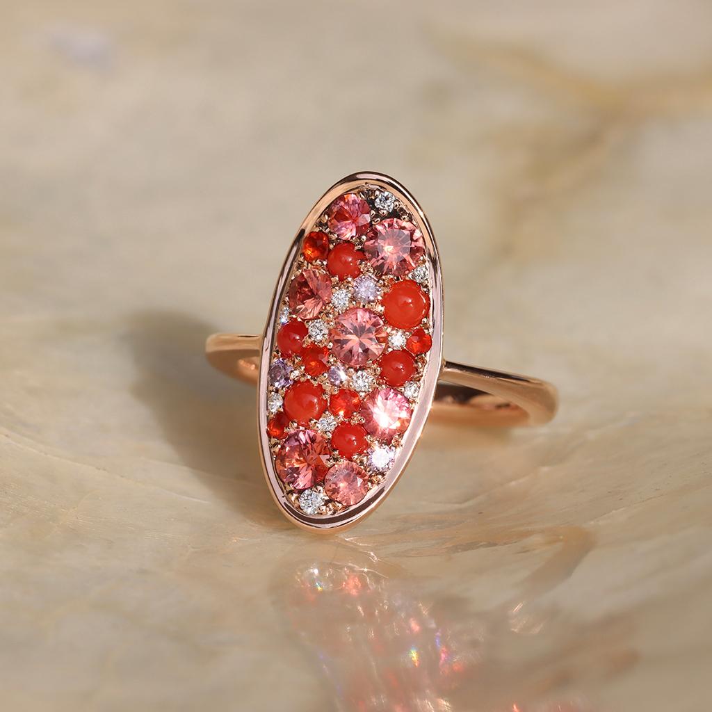 Discover elegance redefined with our 18K Rose Gold Ring, a marvel of exquisite craftsmanship. This ring features an enchanting array of Padparadscha sapphires, known for their mesmerizing lotus-inspired hues, alongside vibrant Coral Cabochons that
