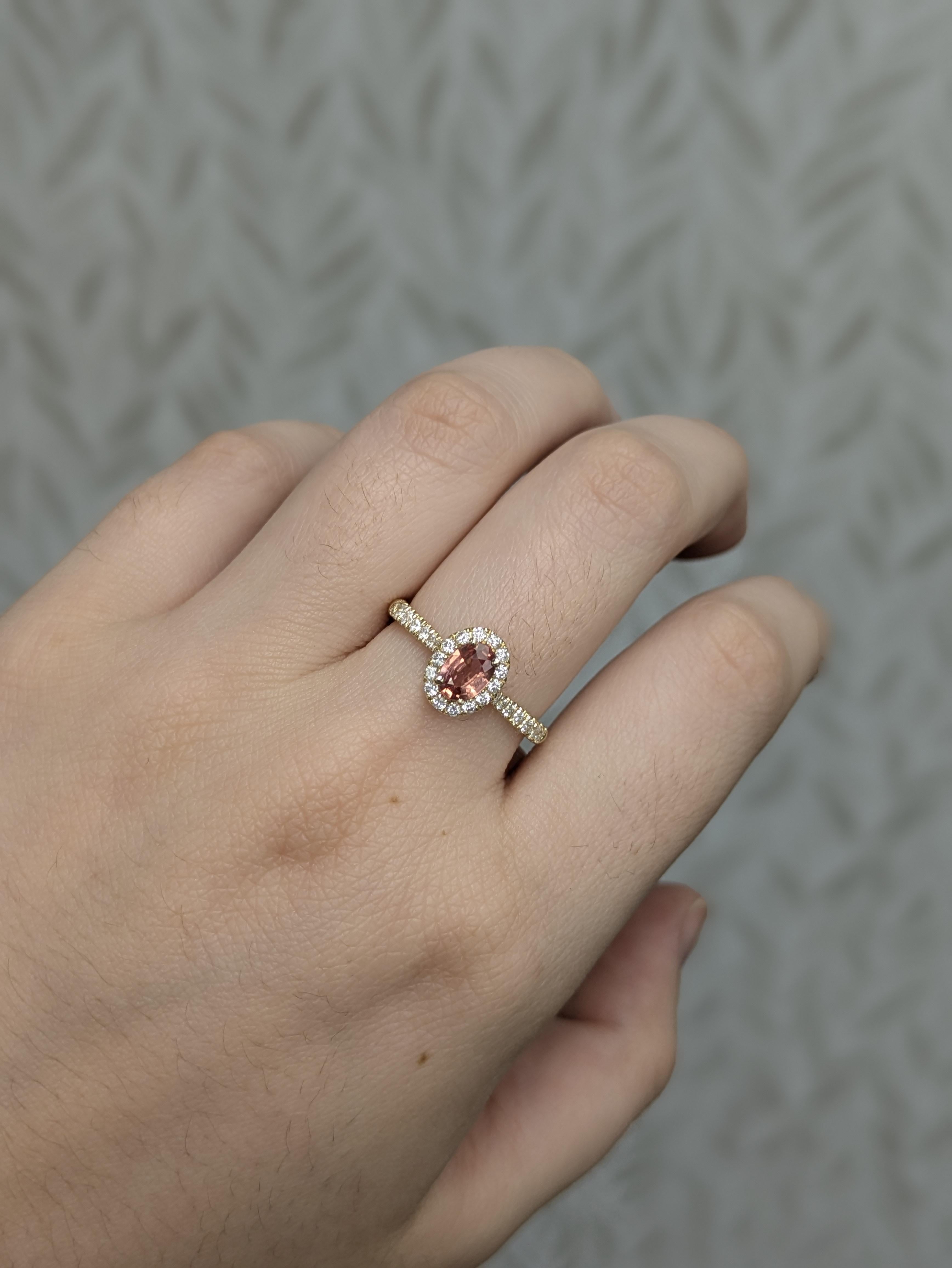 Este refinado anillo lleva un zafiro Padparadscha oval de 0,58 ct (6x4 mm), tratado térmicamente y procedente de Ceilán, famoso por su raro tono rosa anaranjado. Engarzada en 2,24 g de oro de 14 quilates, la piedra central está bellamente acentuada