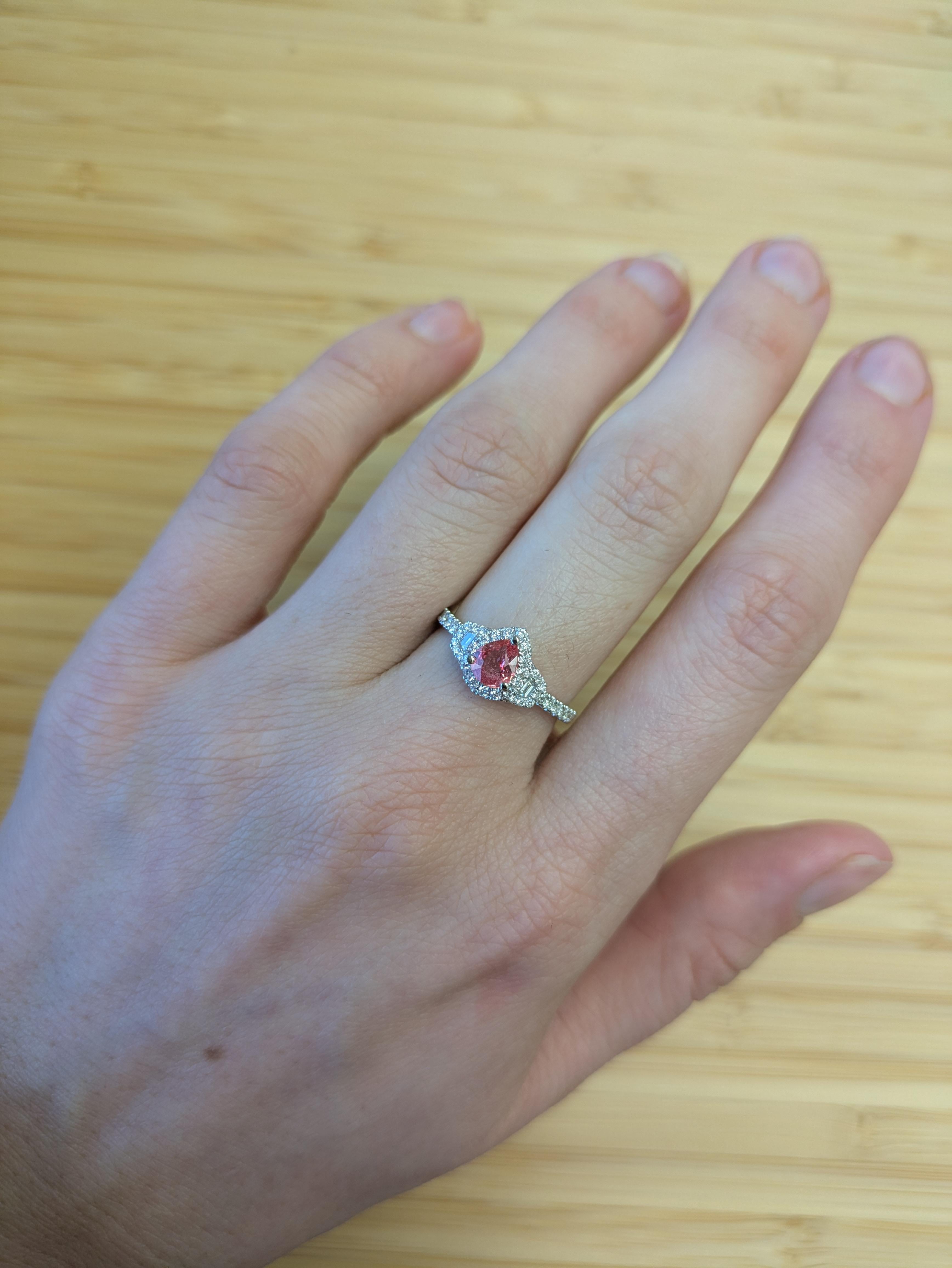 Dieser zeitlos schöne Padparadscha-Saphirring hat einen seltenen pfirsichrosa Mittelstein, der von einem Kranz aus natürlichen, erdgebundenen Diamanten umgeben ist. Das aus massivem 14-karätigem Gold gefertigte Band funkelt mit diamantenen Akzenten