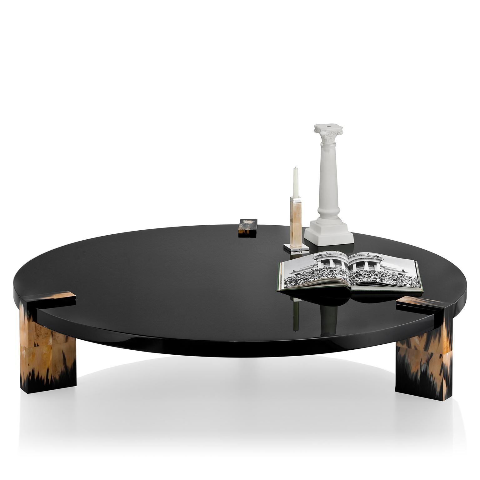 Featuring a round tabletop in wood with lacquered black gloss finish, Paestum coffee table is embellished by three elegant legs in Corno Italiano, whose variegated veining create a striking visual effect drawing attention and attraction to the