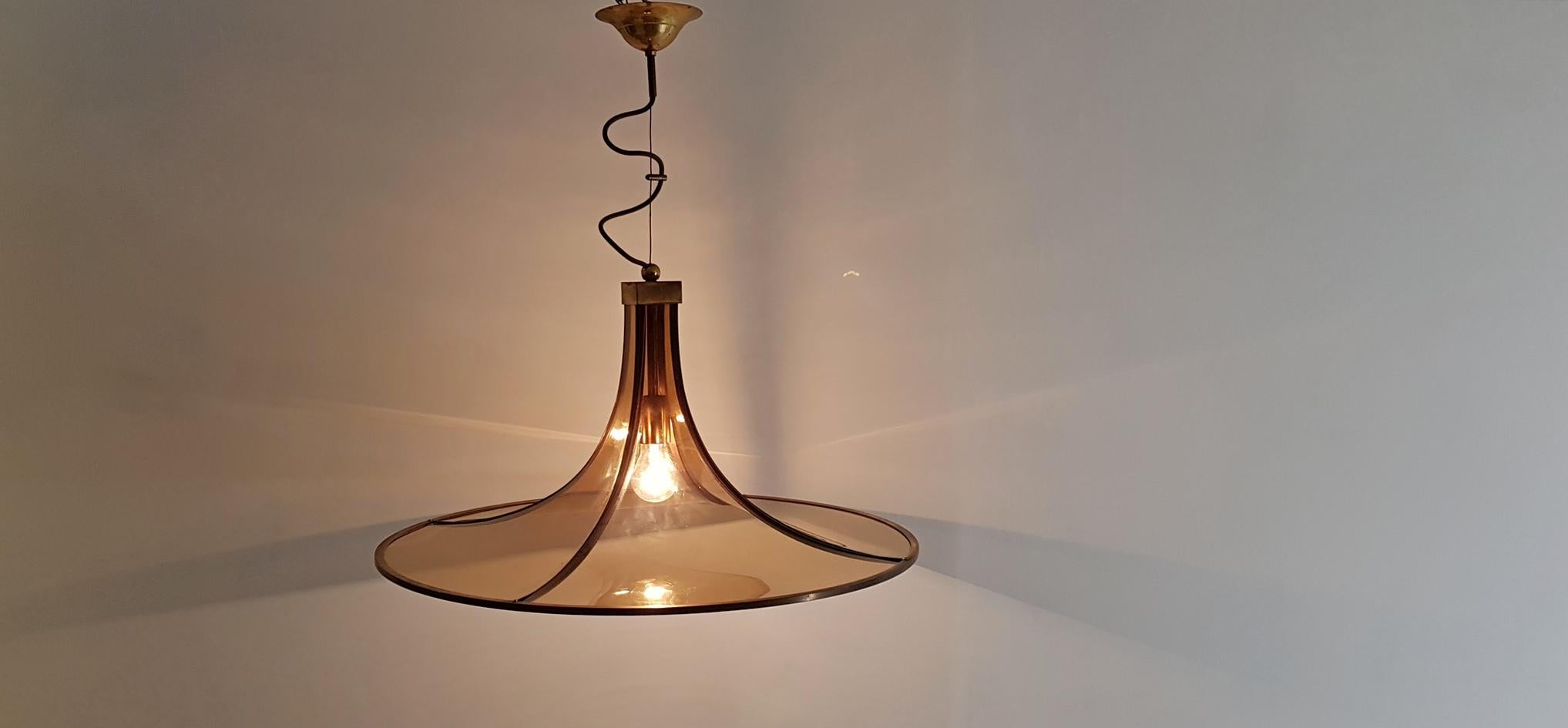 Round pendant lamp by Esperia, Italy with smoke colored glass that gives a warm glow to the room. The glass sits on a brass structure and it uses E40 lightbulbs. Works in the US as well as Europe. The height can be varied with the steel wire. The