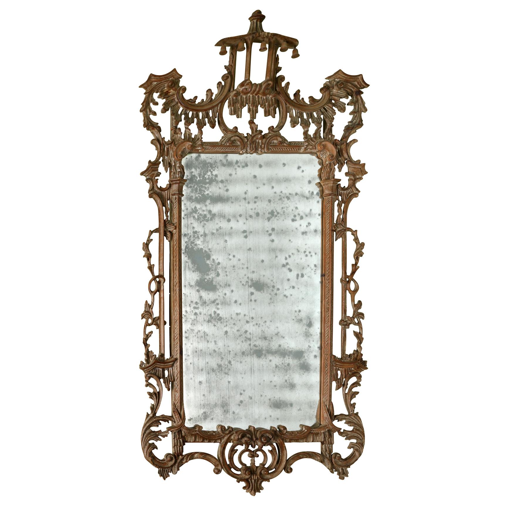 Espejo de época estilo Jorge II con cresta de pagoda y cristal envejecido.  El marco presenta intrincados detalles tallados que incluyen hojas de acanto, brazos con volutas y una cresta en forma de pagoda con pequeñas campanillas colgantes.  El