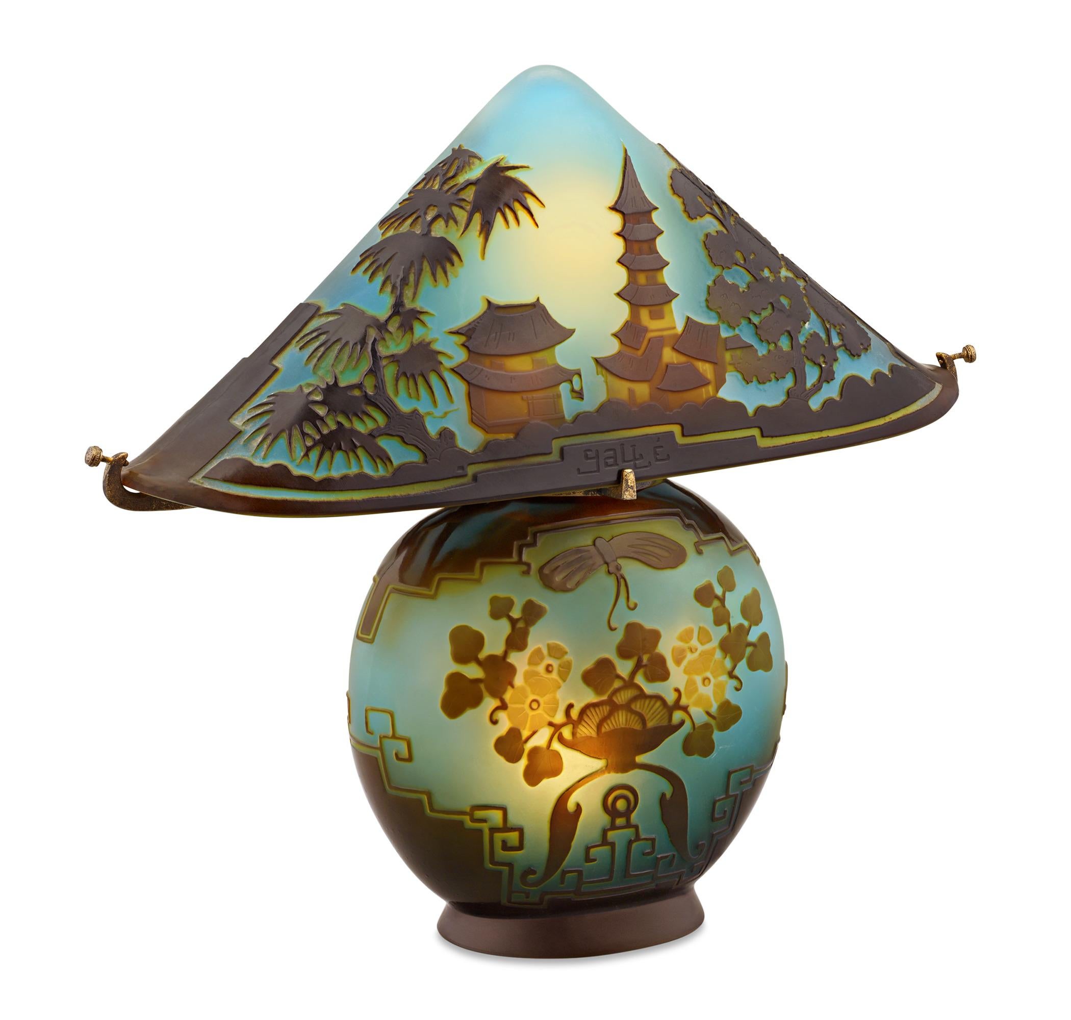 This Pagoda Cameo glass lamp is a highly rare and coveted example of Émile Gallé's mastery of glassmaking. Layers of vibrant color, from golden yellows to mauve, radiate from a background of elegantly frosted blue-green glass to form the scene of an