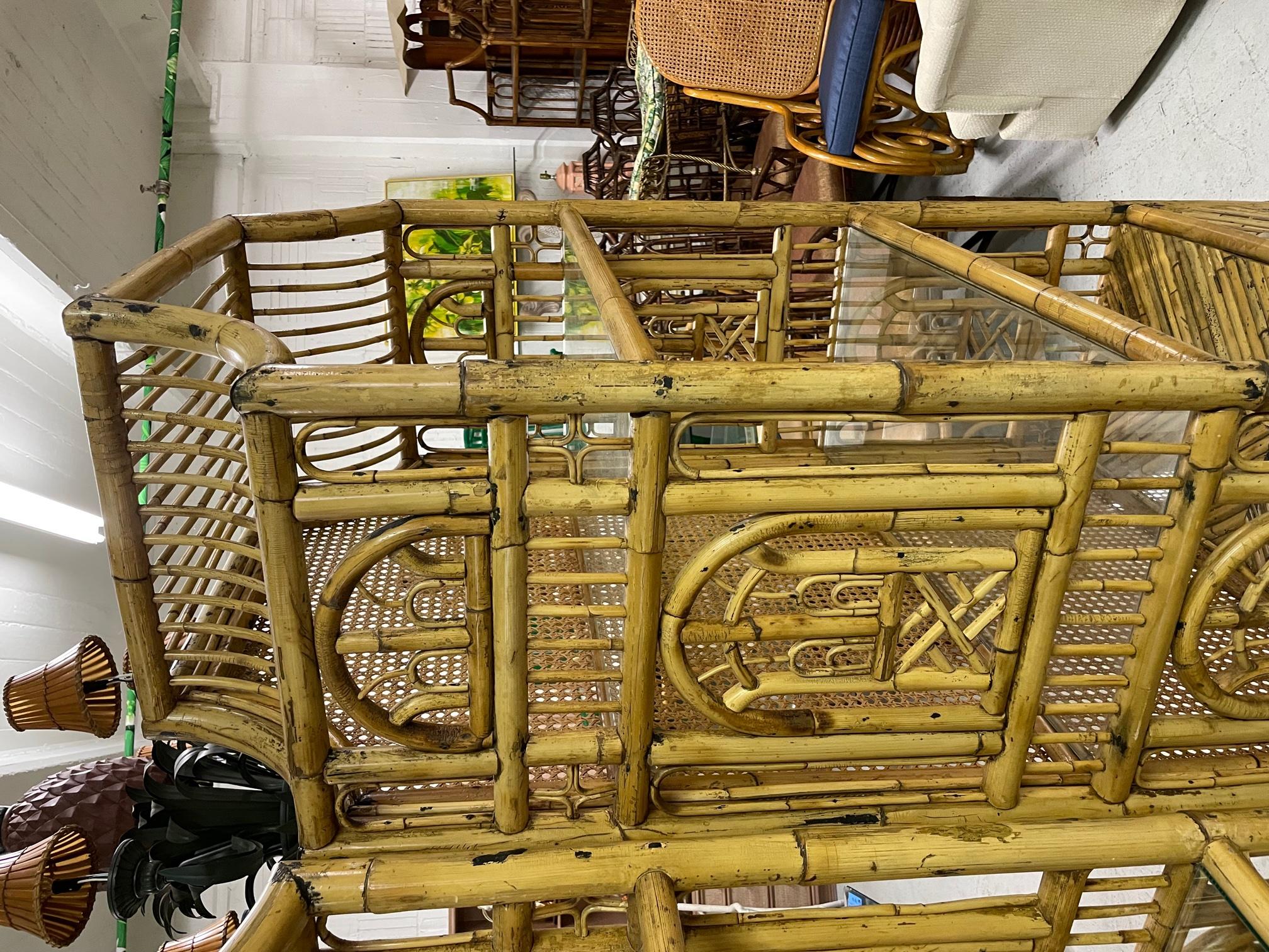 Pair of large Asian chinoiserie style etageres feature full rattan construction with intricate Chinese chippendale fretwork and double door storage. Two glass shelves above lower rattan shelf. Brass hardware. Full cane back. Very good condition with