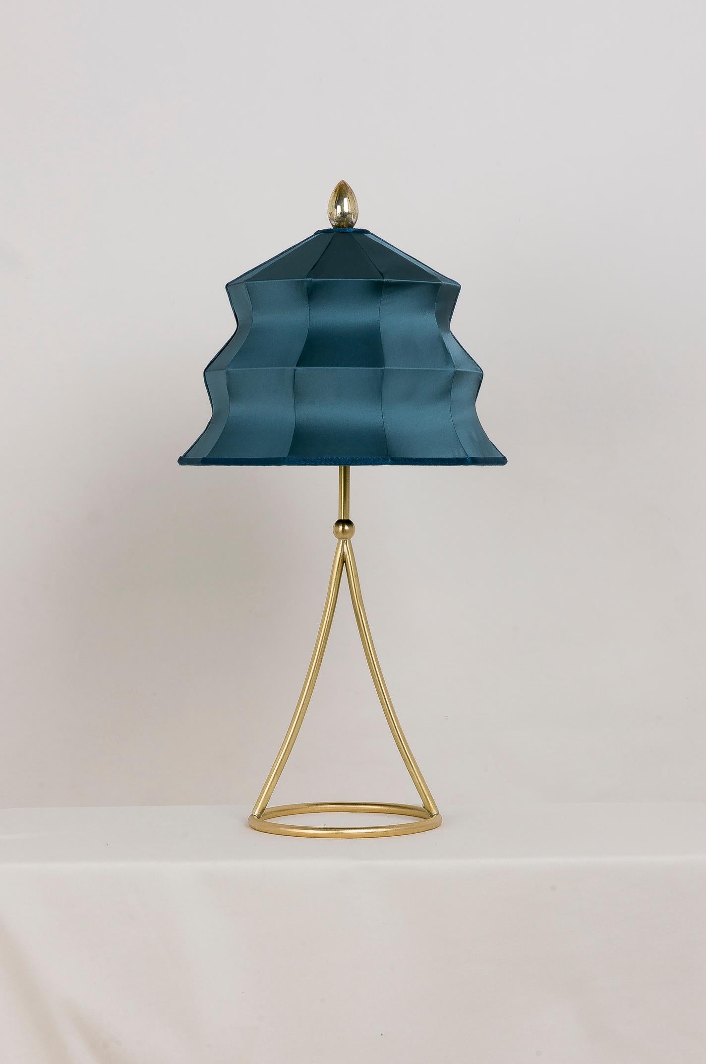 This table lamp is a contemporary piece, entirely made in Tuscany and manufactured in an artisanal way. 

The brass stem restores a rounded and sensual stability; calm and serenity enshroud the lampshade in silk satin. A silvered crystal tip at
