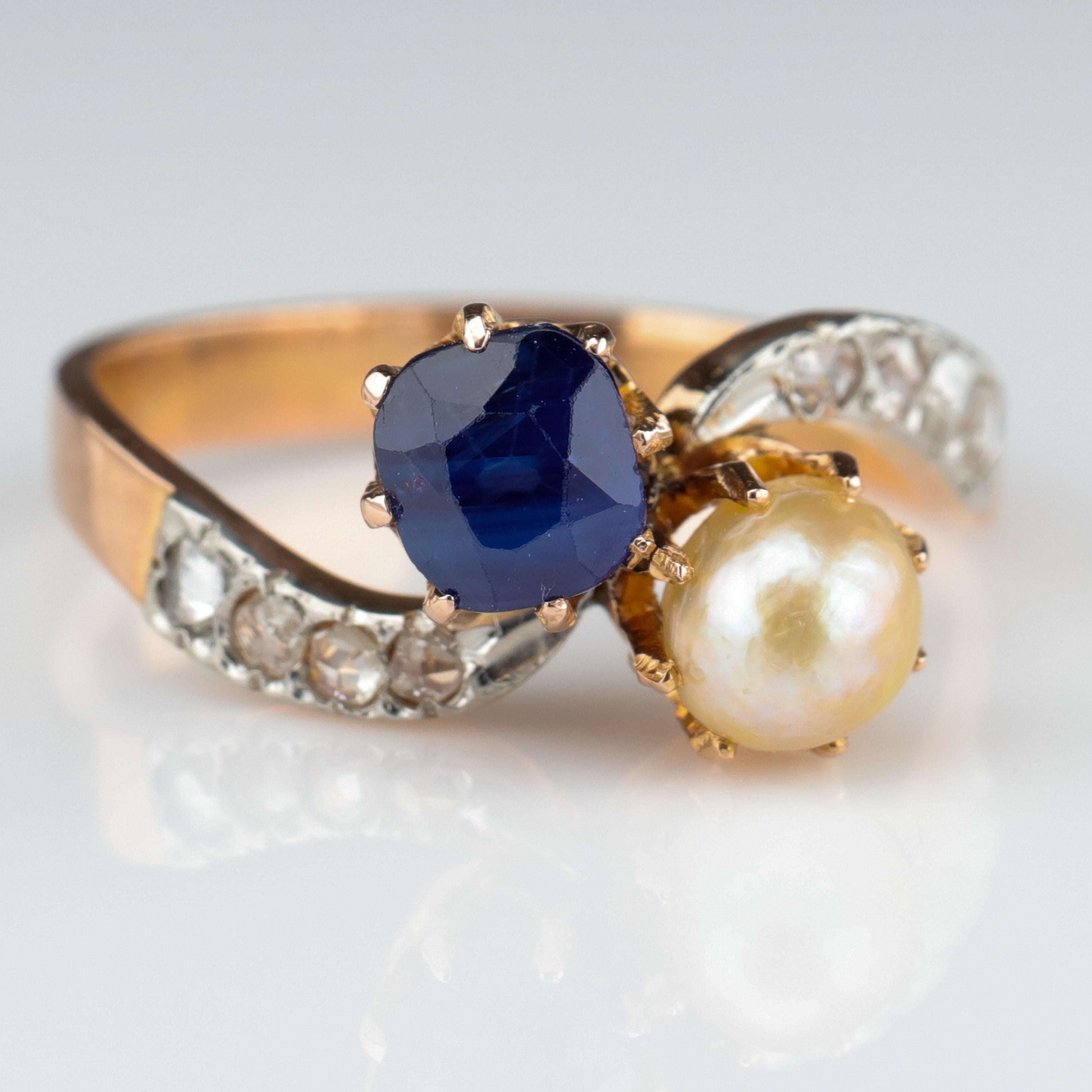 This magnificent French Art Nouveau crossover toi et moi (you and me) ring was handcrafted near the turn of the previous century from 18K rose gold and platinum. Elegantly formed prongs hold one natural 5.12 mm 3/4 pearl and one .70 carat triumphant