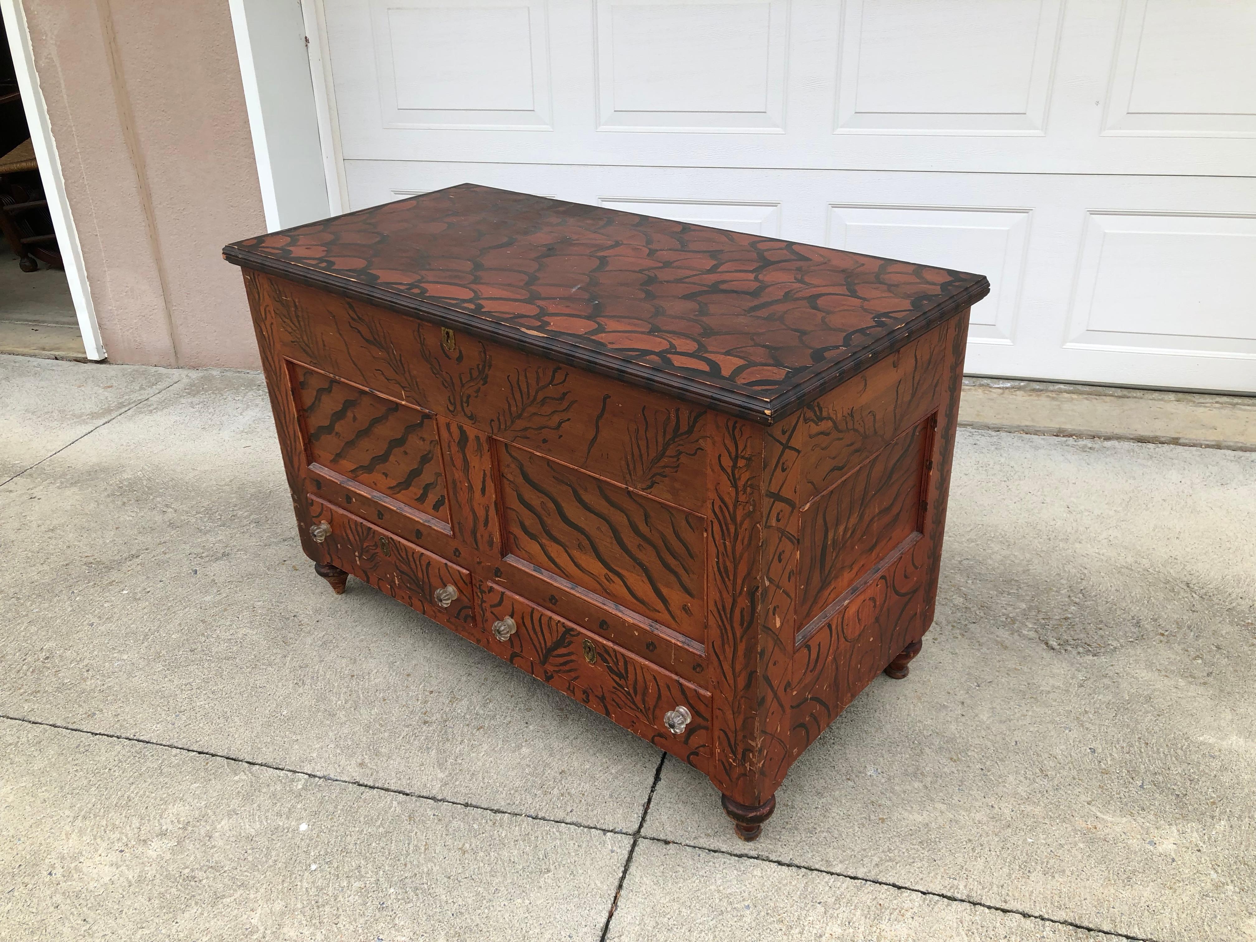 Having a thumb-molded top opening to a well interior with a till, the conforming case with an applied base molding is supported by turned feet. The piece is complemented with a rare and unusual free hand painted decoration of lozenges and dots trees