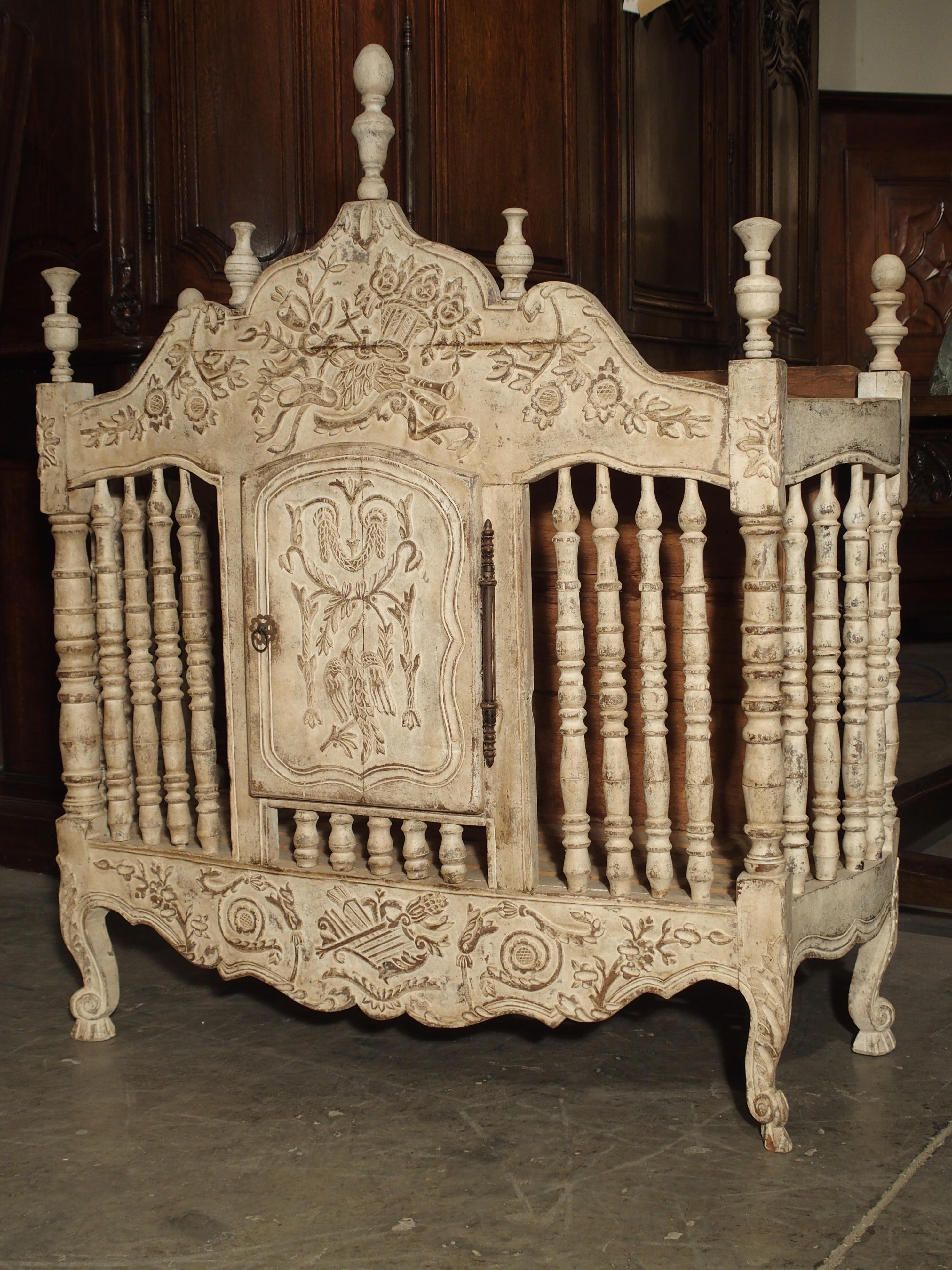 This antique French, painted panetiere is from Provence, France. Multiple motifs of various flowers, musical instruments, C-and S-Scrolls, baskets, ribbons and acanthus leaf detail are on the frieze, the door, and the apron. Turned spindles are on