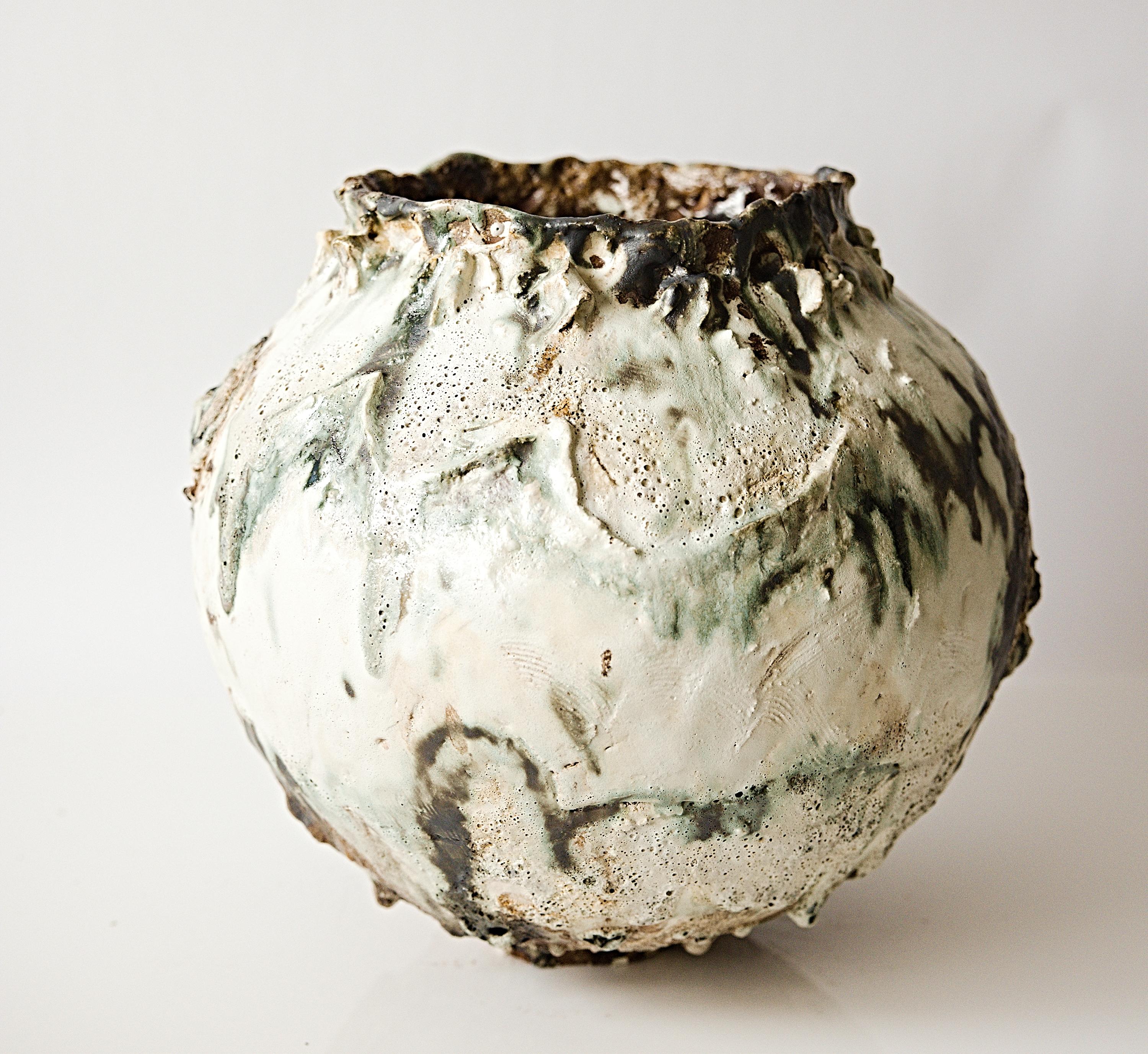 Descubre el arte intemporal con la Serie 25 Pintada - Vasija I de The Shine Studios, que presenta una base mate crema con efectos únicos pintados a mano mediante óxidos y esmaltes. Adoptando la estética wabi-sabi, este jarrón escultural presenta una