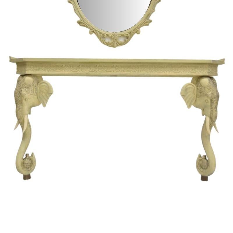 A painted and carved elephant console table and mirror set. Crafted with precision, the console table features legs of intricately sculpted elephant heads, complete with gracefully curved trunks and tusks. Each element of the elephant design is