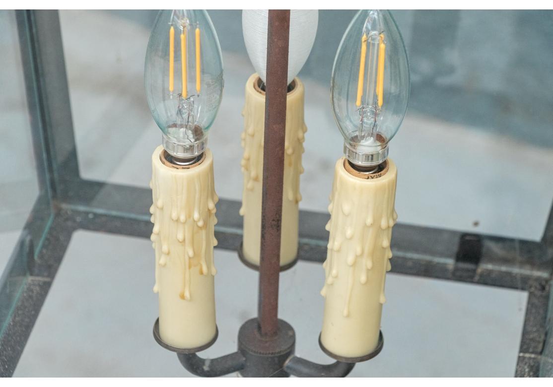 La elegante y espectacular linterna de tres luces de gran tamaño tiene un cristal cuadrado clásico y un marco pintado de negro. Está decorado con hileras de hojas pintadas de verde en la parte superior sobre las grandes hojas de acanto curvadas y