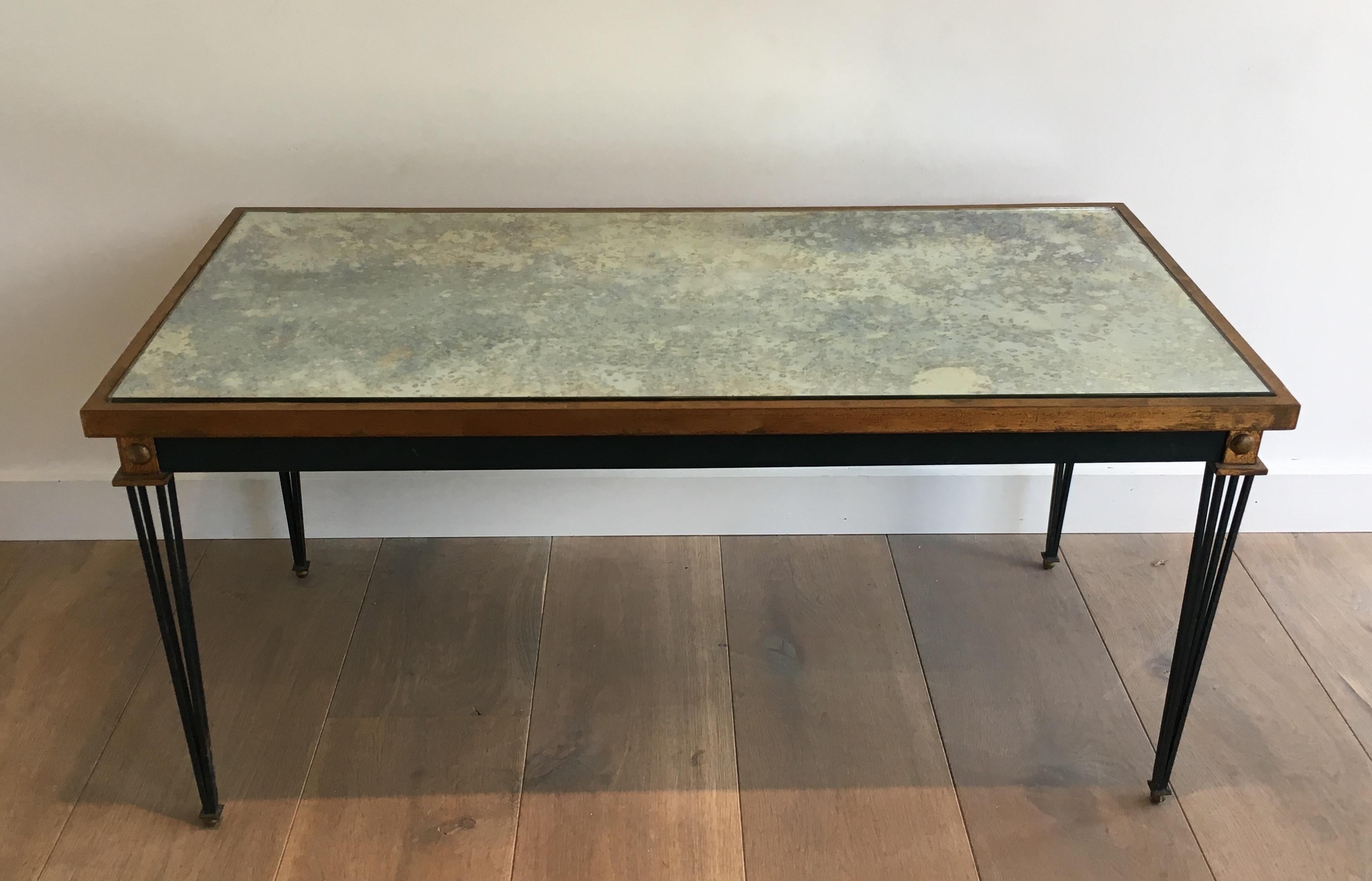 This coffee table is made of painted and gilt steel with a faux-antiques mirror (a little bit damaged on a corner). This is a work in the style of famous French designer Jacques Quinet, circa 1940.