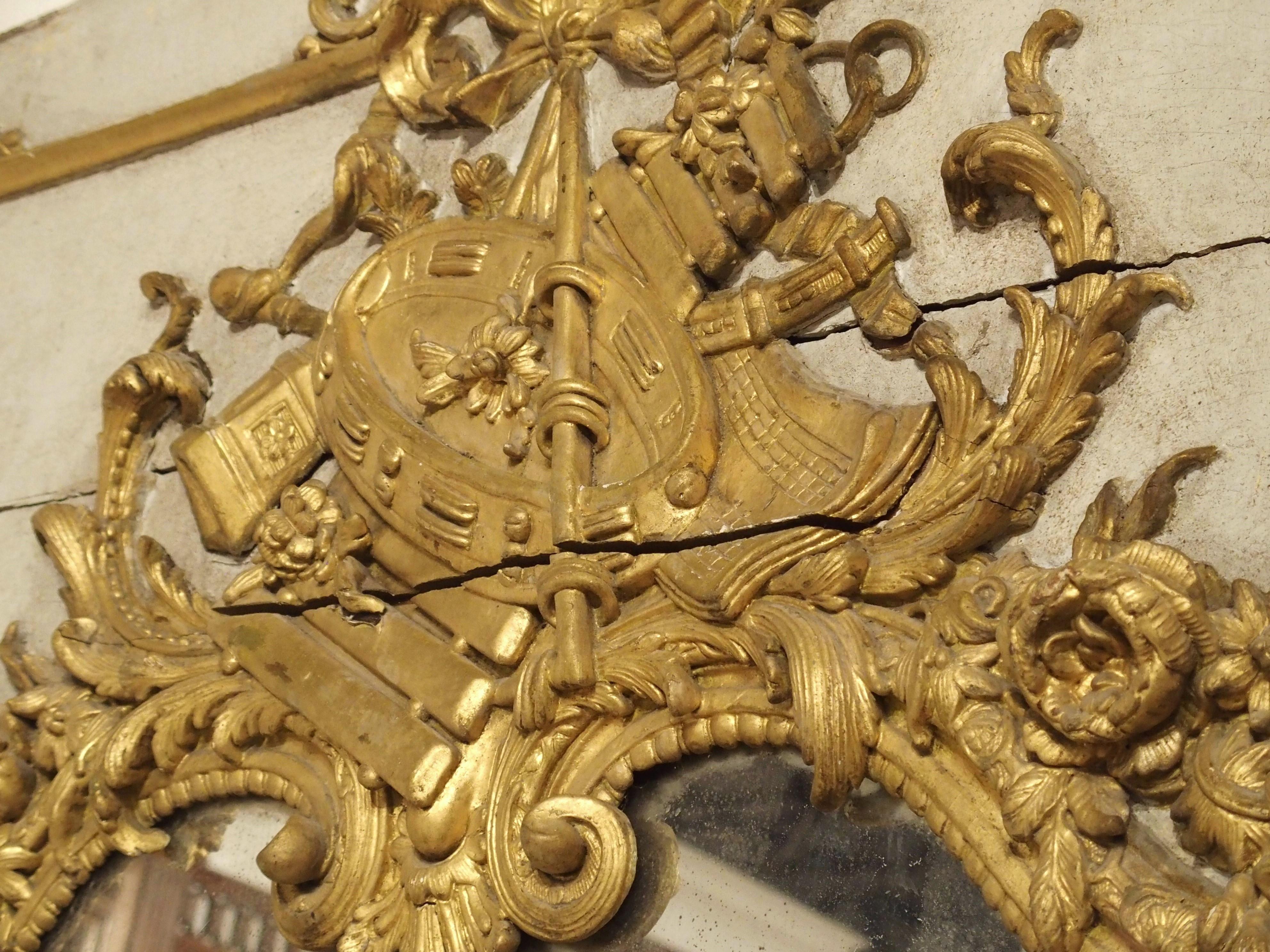 Dieser sehr große Trumeau-Spiegel wurde kürzlich auf dem Dachboden eines Schlosses in der Normandie, Frankreich, entdeckt. Der schöne Spiegel, der sowohl handbemalte als auch vergoldete Elemente aufweist, wurde um 1720 handgeschnitzt und ist somit