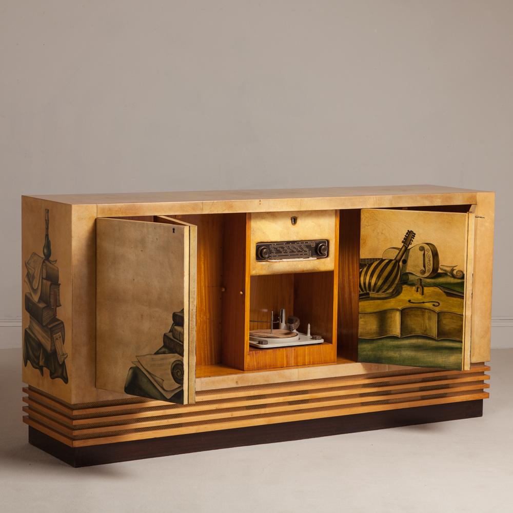 Lacquered goatskin music cabinet by Aldo Tura with concertina doors to the front and Back. The front doors are painted with string instruments amongst objet and to the sides are books. The interior has the original music system (not tested) and