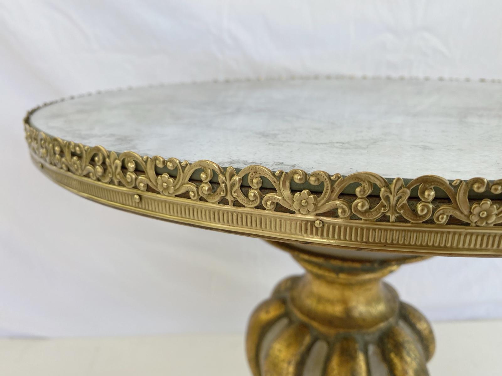 Side table, painted and parcel gilt finishes; having a round top of aged mirrorplate, bordered by a pierced, scrolling gallery of rosettes and fleur de lis, raised on a spiral-turned, ballustrade-form pedestal, ending on a round foot, and graduated