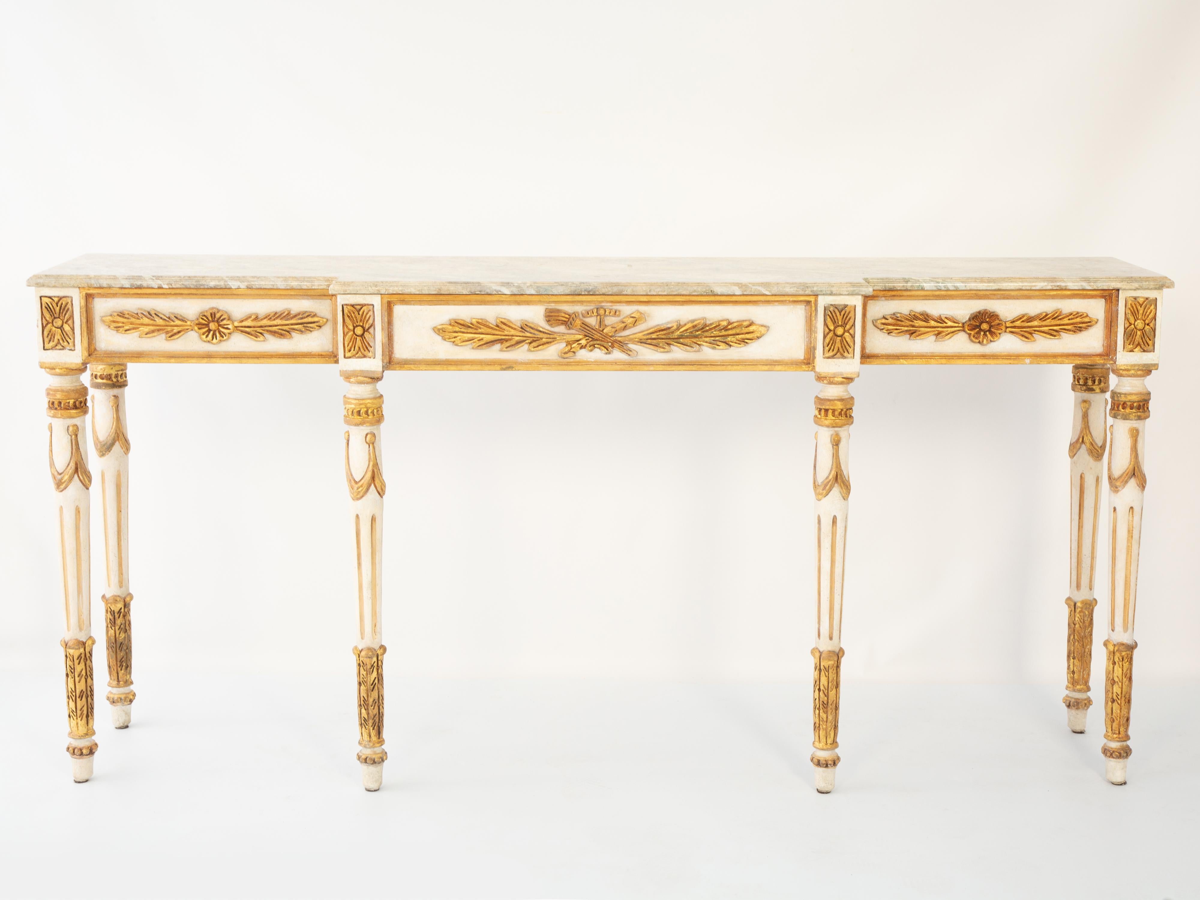 Tavolo consolle dalle proporzioni lunghe e strette, in stile Luigi XVI. Il suo piano a ribalta finto dipinto, su un tavolo con finitura color crema e dorata a pacchi, mostra un'usura naturale. Il grembiule campito è intagliato con rosette, acanti e
