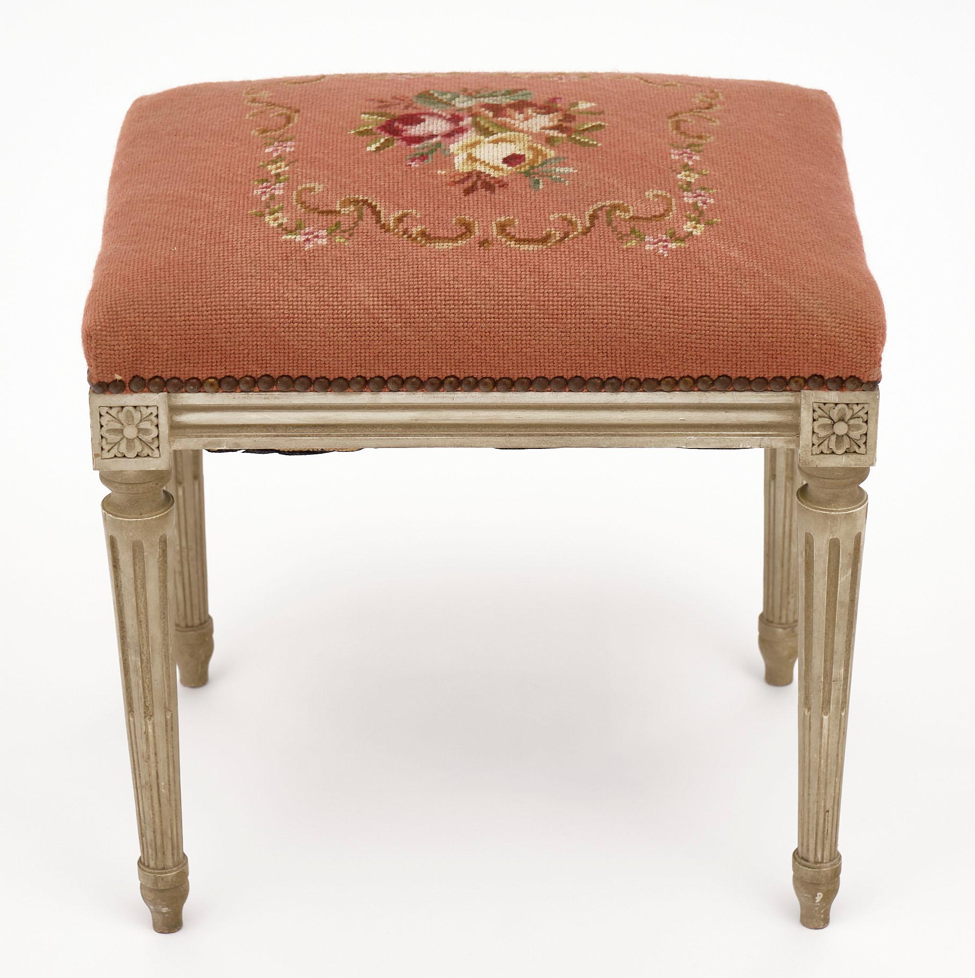 Painted antique French stool in the Louis XVI style with original salmon colored; embroidered wool tapestry. We love the fluted legs with original patinated gray paint.