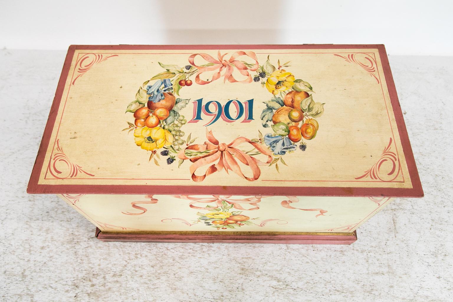 The top of this blanket chest is hand painted with a wreath of fruit, flowers, leaves, and bow tied ribbons. The front is painted with a bow tied ribbon suspending a spray of flowers, fruit, and leaves.
  