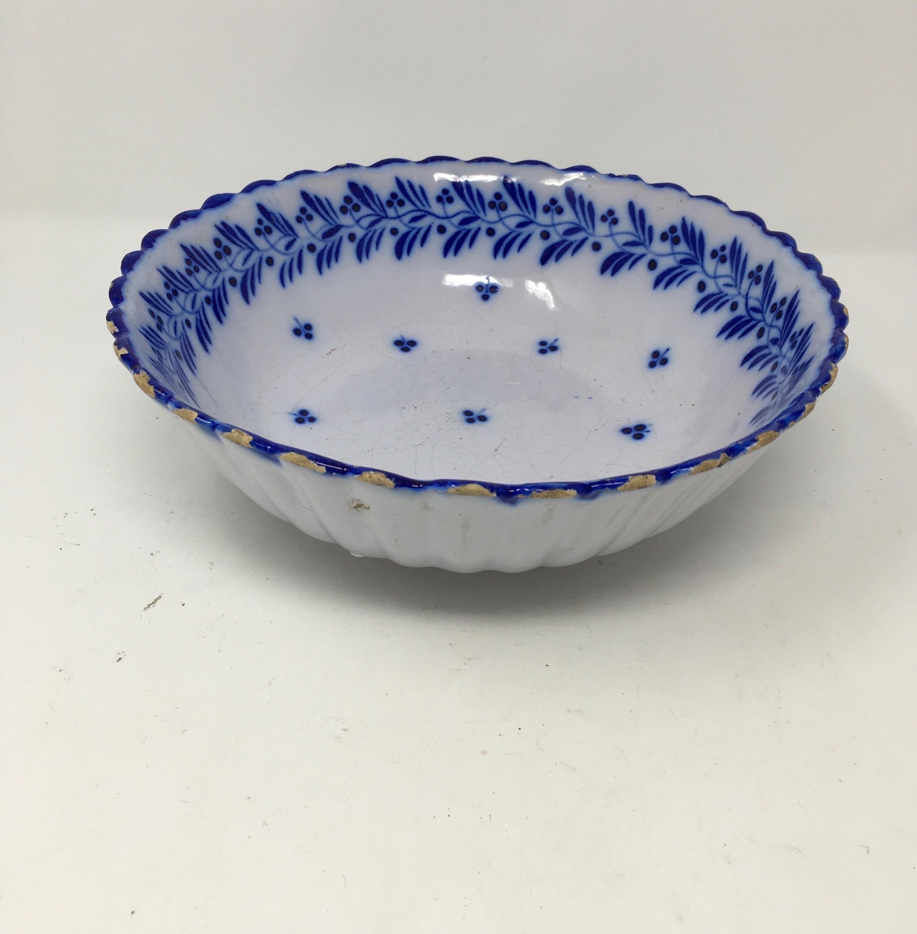 This cheerful blue and white painted bowl has a small scalloped rim. It is finished on the interior edge with a leaf and berry design. Its vivid blue color makes it a lovely display piece or a must have for blue and white collectors. There is a
